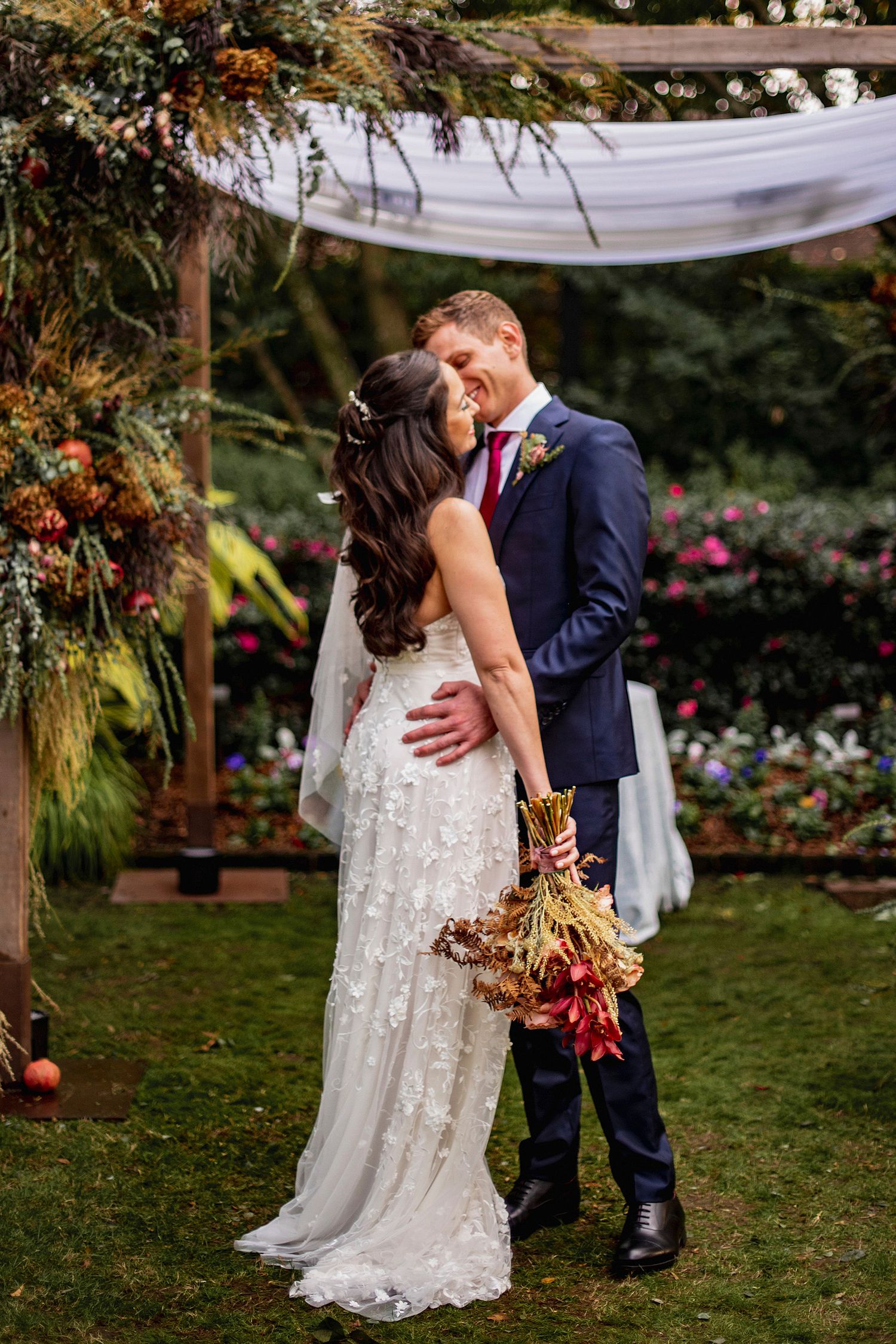 Wedding couple sharing intimate moment in garden with autumn decorations.