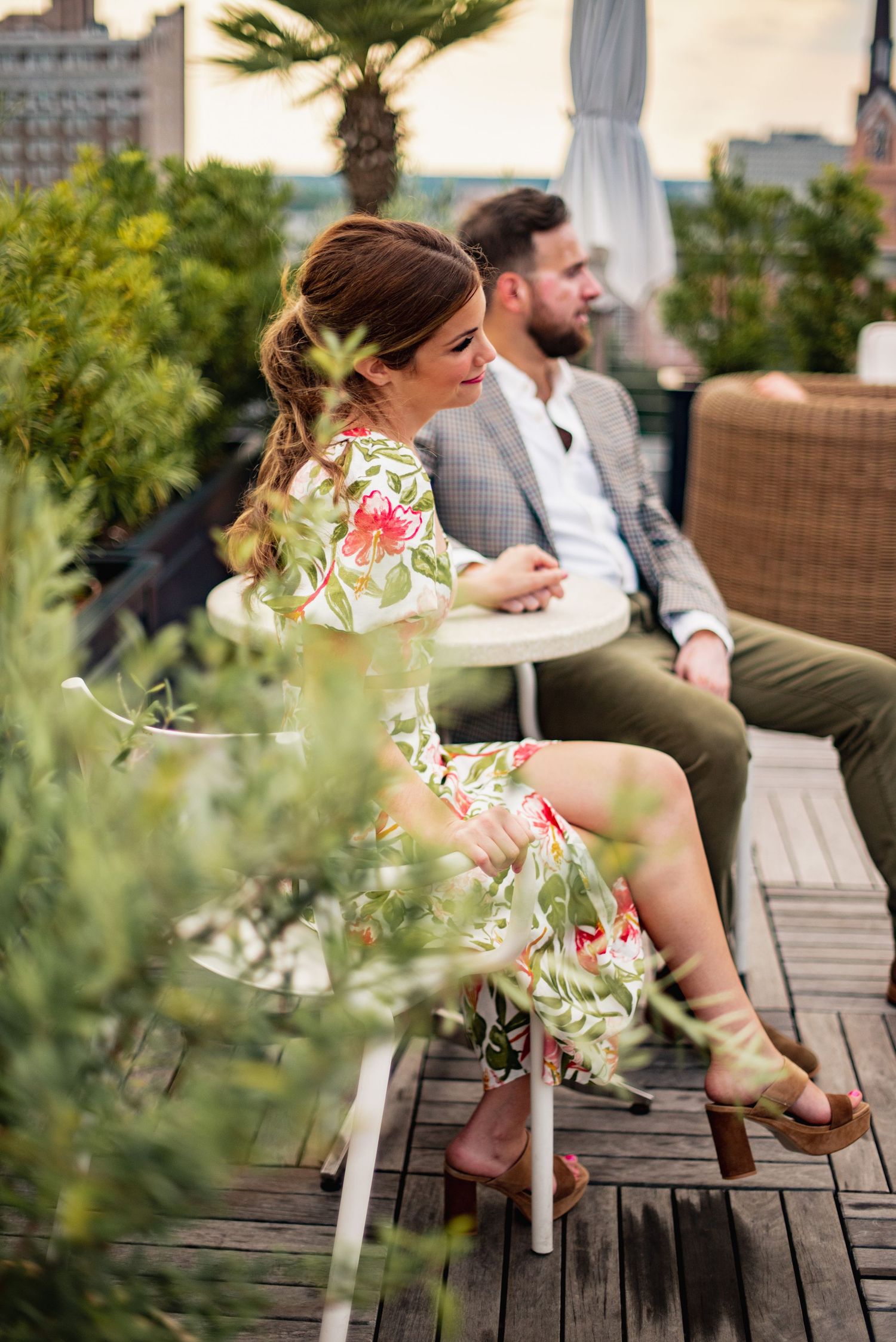 Couple sitting on outdoor deck furniture with floral dress detail visible.