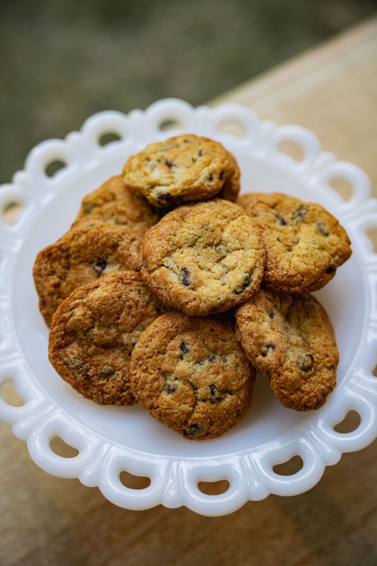 Homemade chocolate chip cookies arranged on white decorative serving plates with scalloped edges.