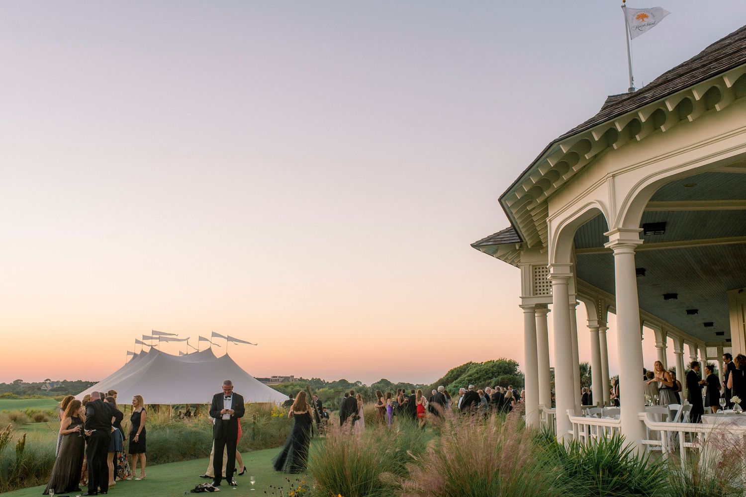 Elegant golf club venue with a covered veranda overlooking a sunset ceremony setup with mountain views.