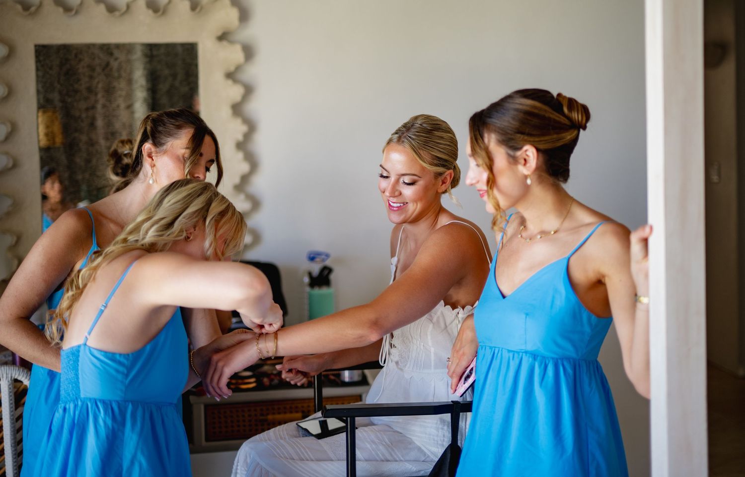 Wedding party in light blue dresses getting ready together in a bright room.