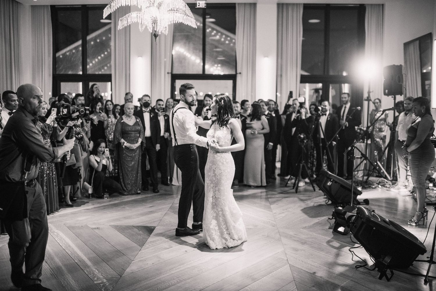 Black and white panoramic view of a crowded ballroom during an evening wedding reception celebration.