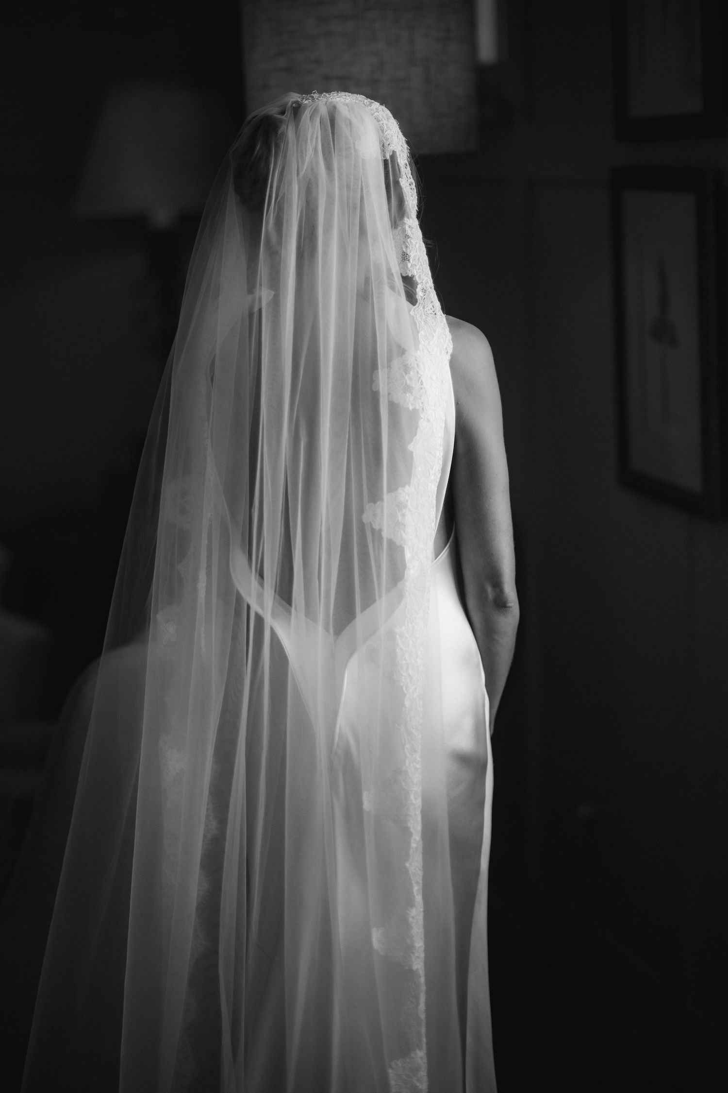 A series of black and white photos showing the silhouette of a bride's wedding veil and dress in dramatic lighting.