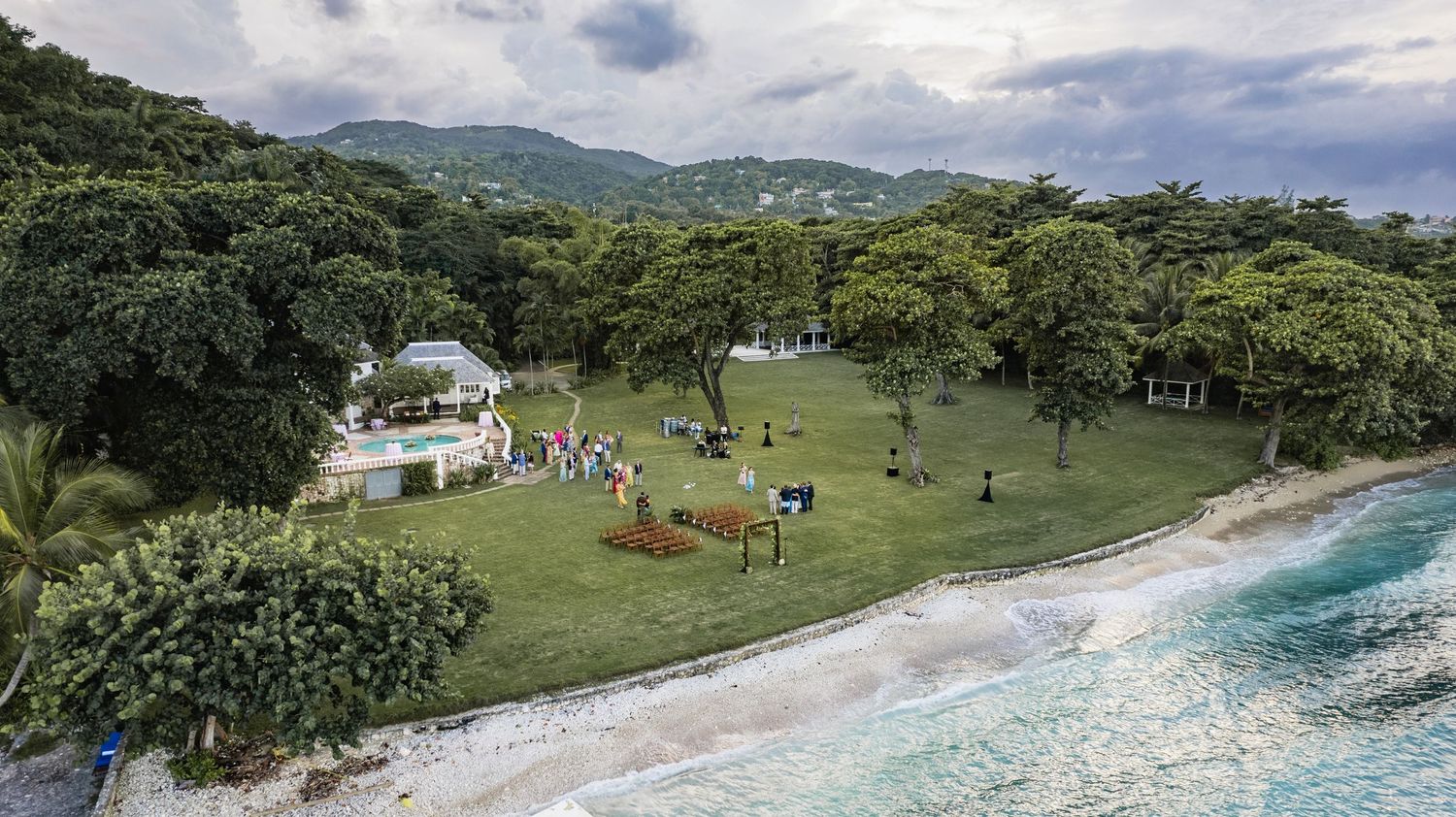 Aerial view of people enjoying a scenic beach park with turquoise waters and lush tropical vegetation in Hawaii.
