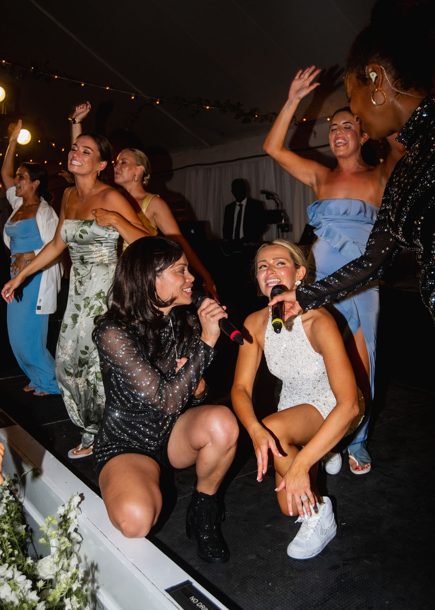 Wedding guests dancing and singing at a lively reception party.
