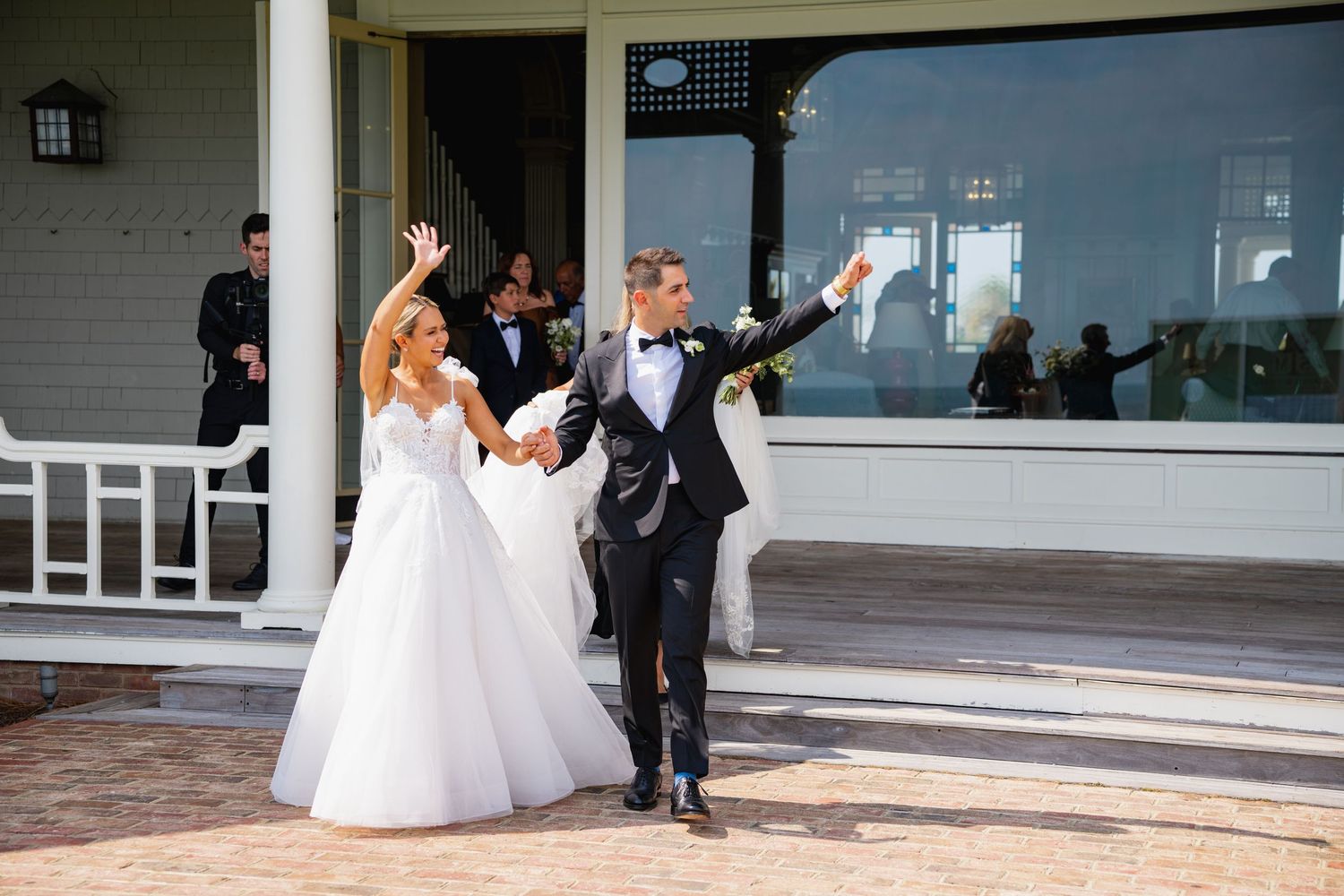 Wedding party members dance and celebrate on an outdoor patio during a reception celebration.