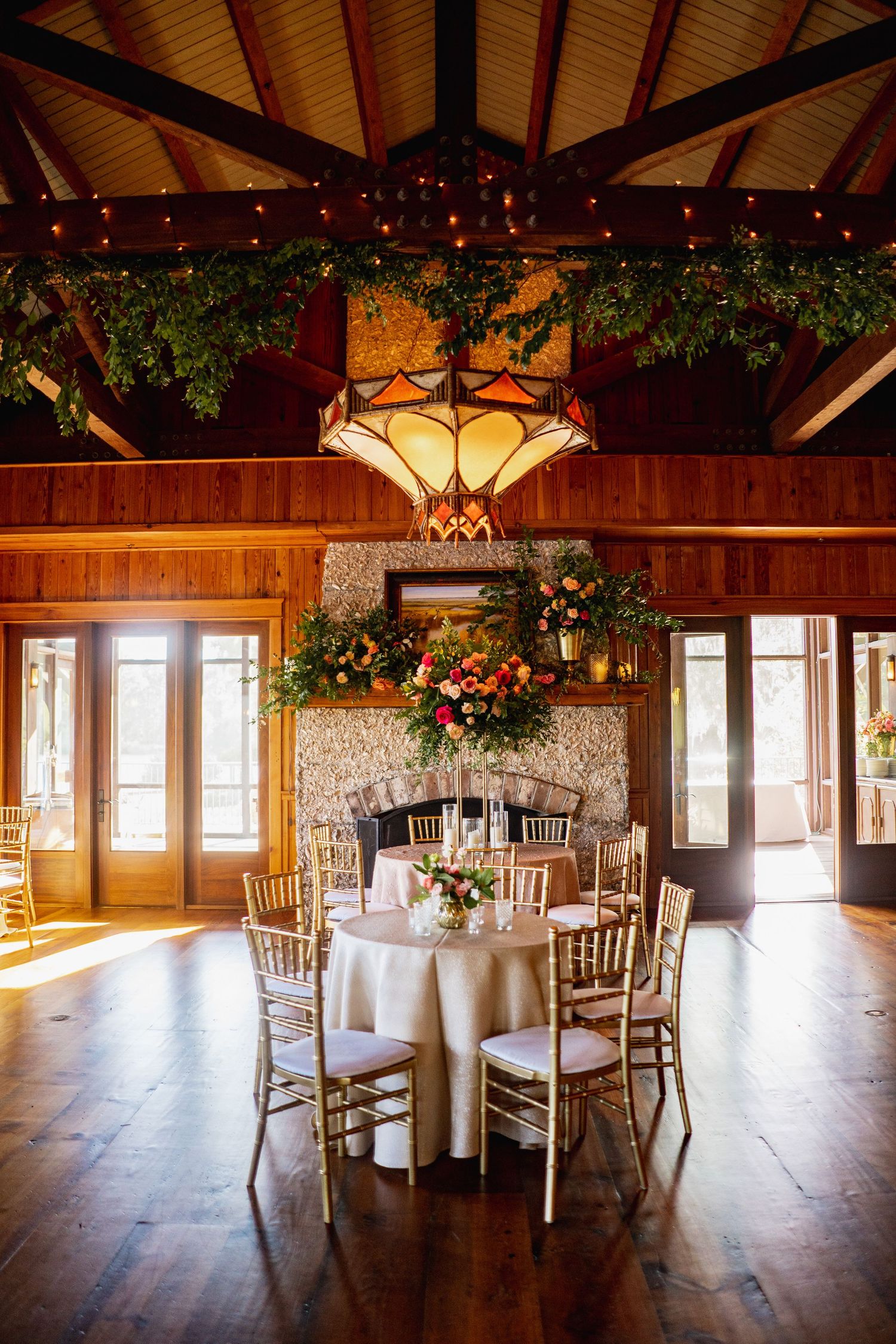 Elegant reception hall with exposed wooden beams, stone walls and round tables set for a formal event.