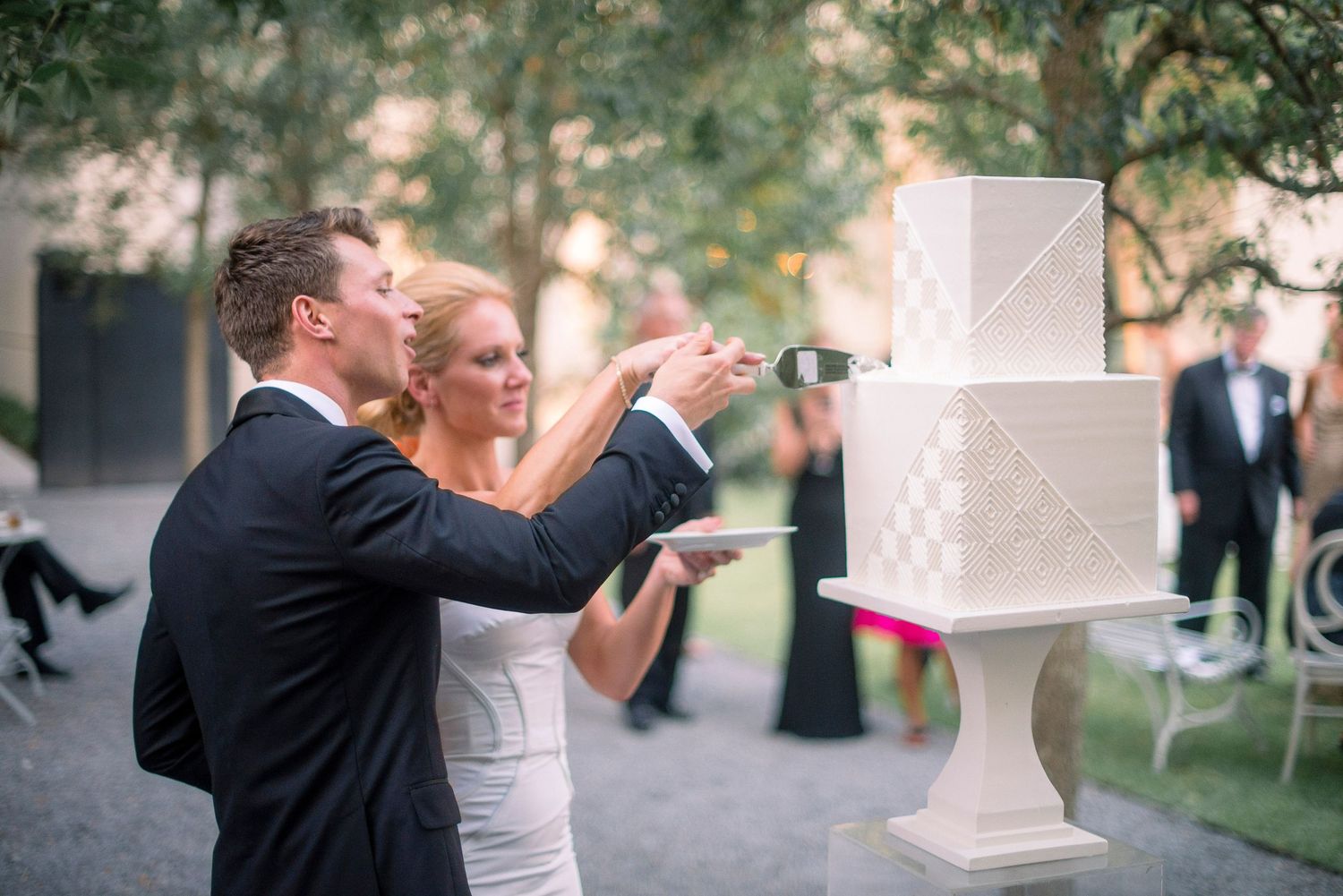 A wedding couple shares an intimate kiss in a garden setting with blurred background foliage.