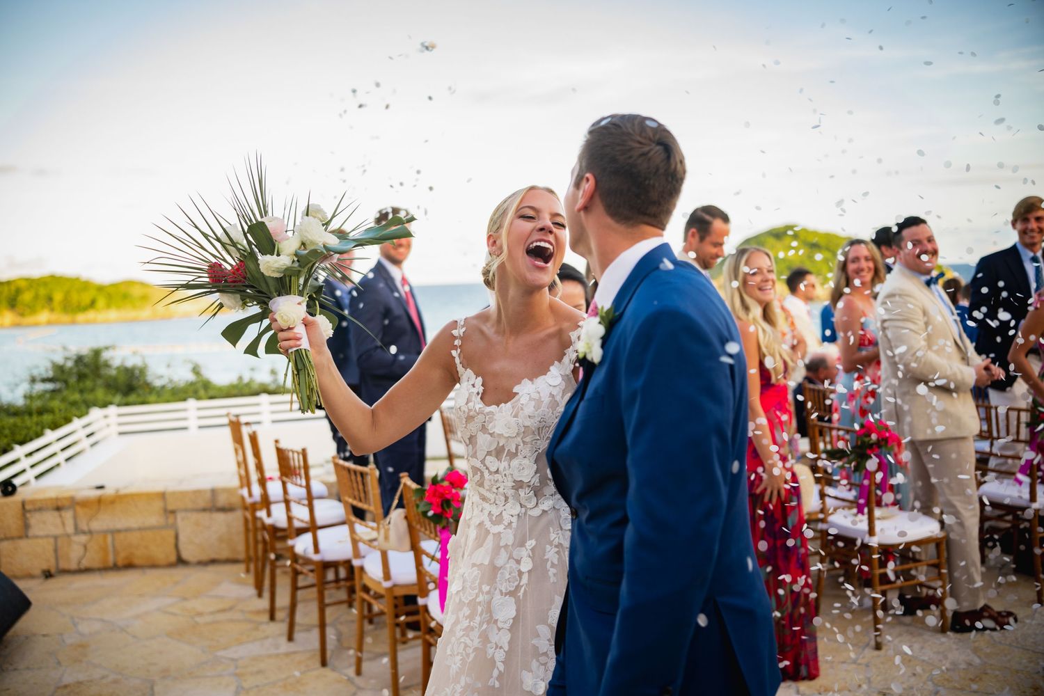 Joyful wedding celebration moment with confetti flying in the air at an outdoor ceremony.