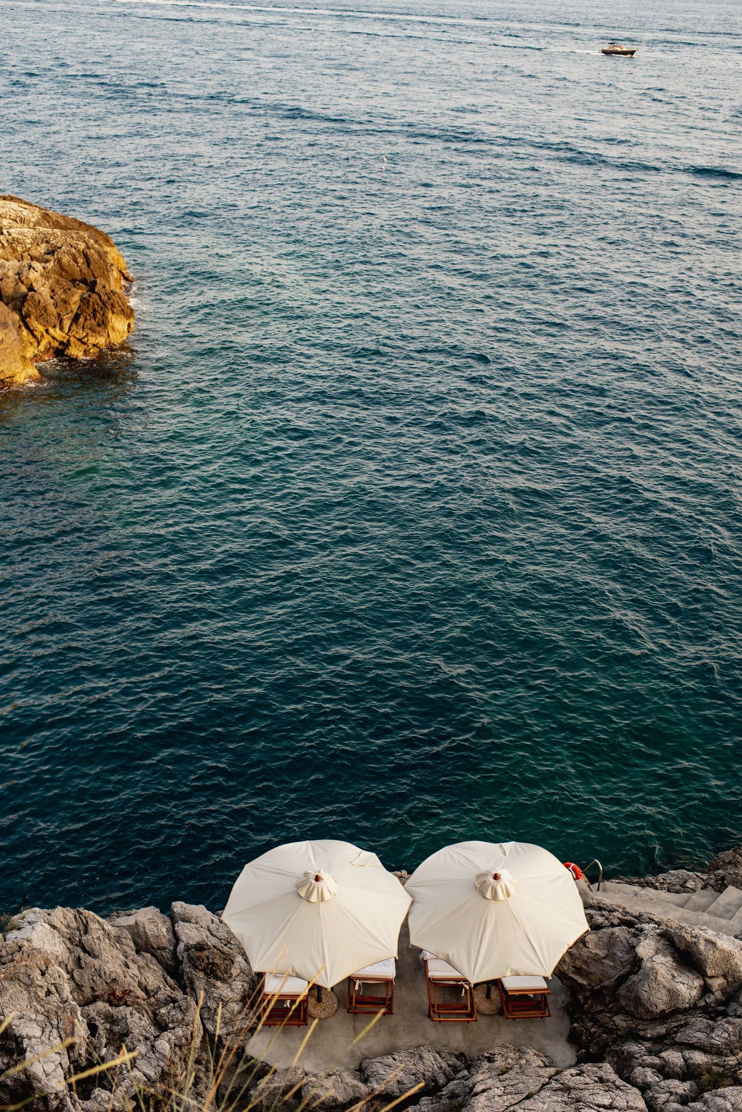 White beach cabanas perched on Amalfi Coast overlooking deep blue Mediterranean waters.