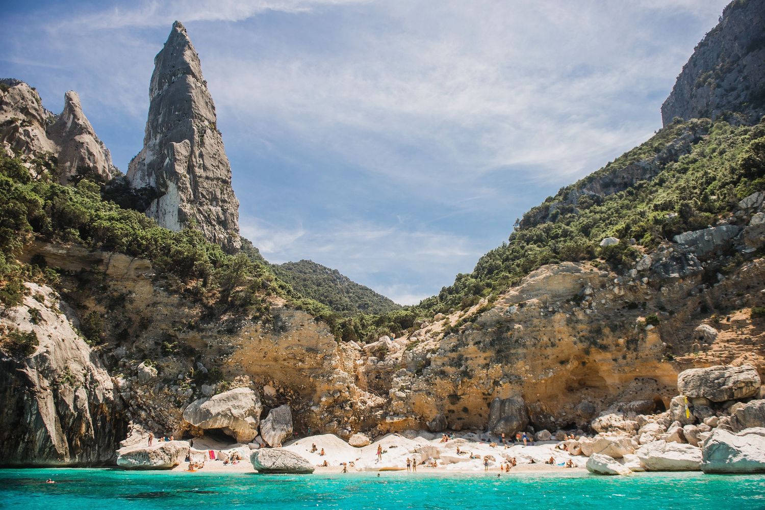Stunning aerial view of a secluded Mediterranean beach cove with turquoise waters and dramatic limestone cliffs.