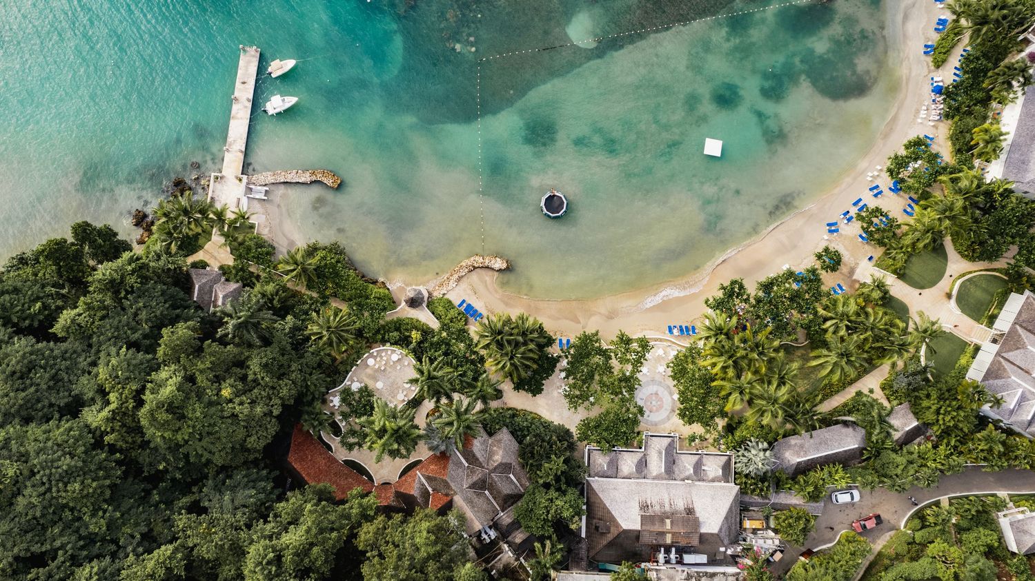 Aerial panoramic view of a tropical coastline with turquoise waters, sandy beaches and lush green vegetation.
