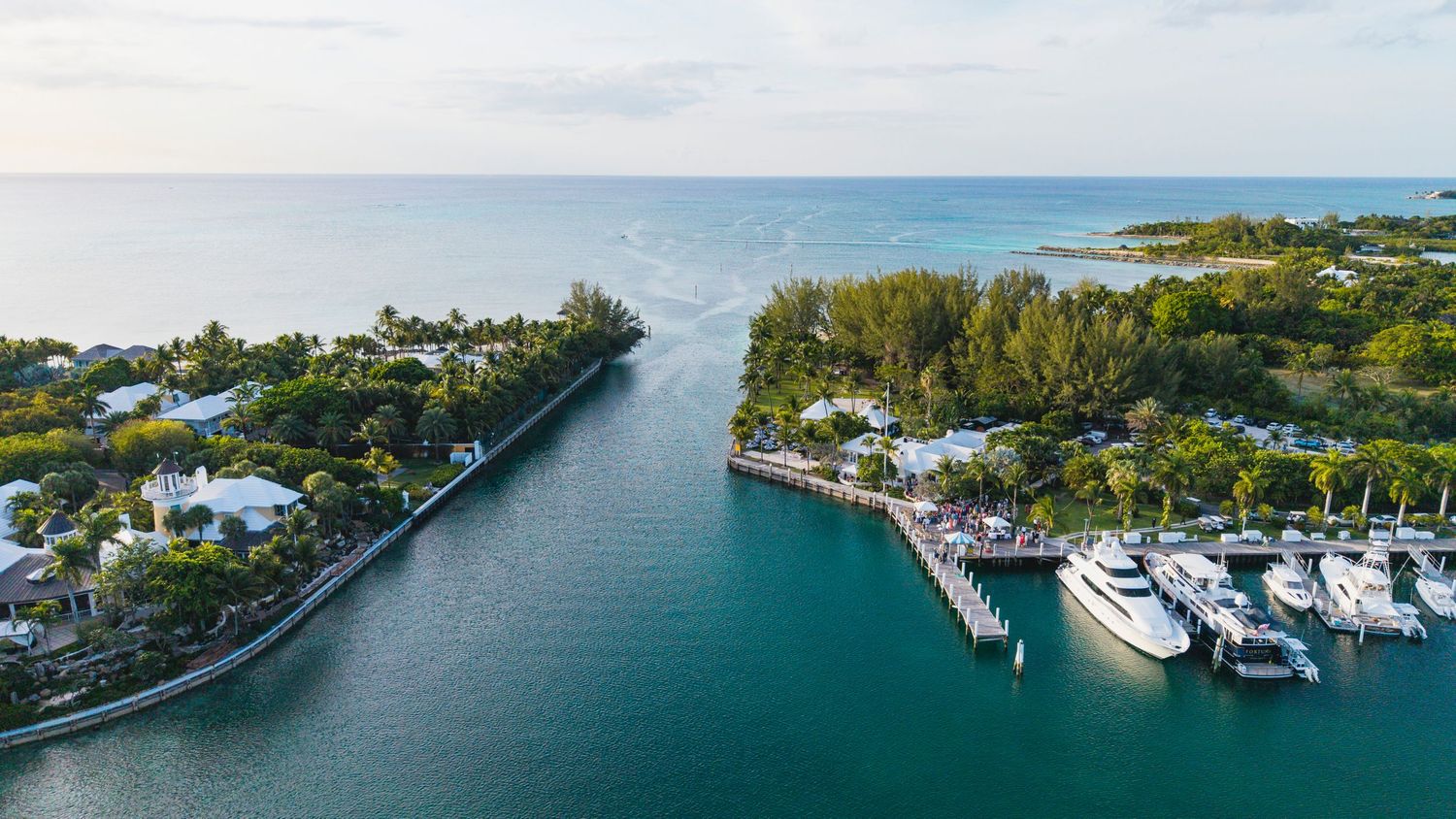Aerial view of a coastal marina with boats docked along the waterfront and tropical vegetation.