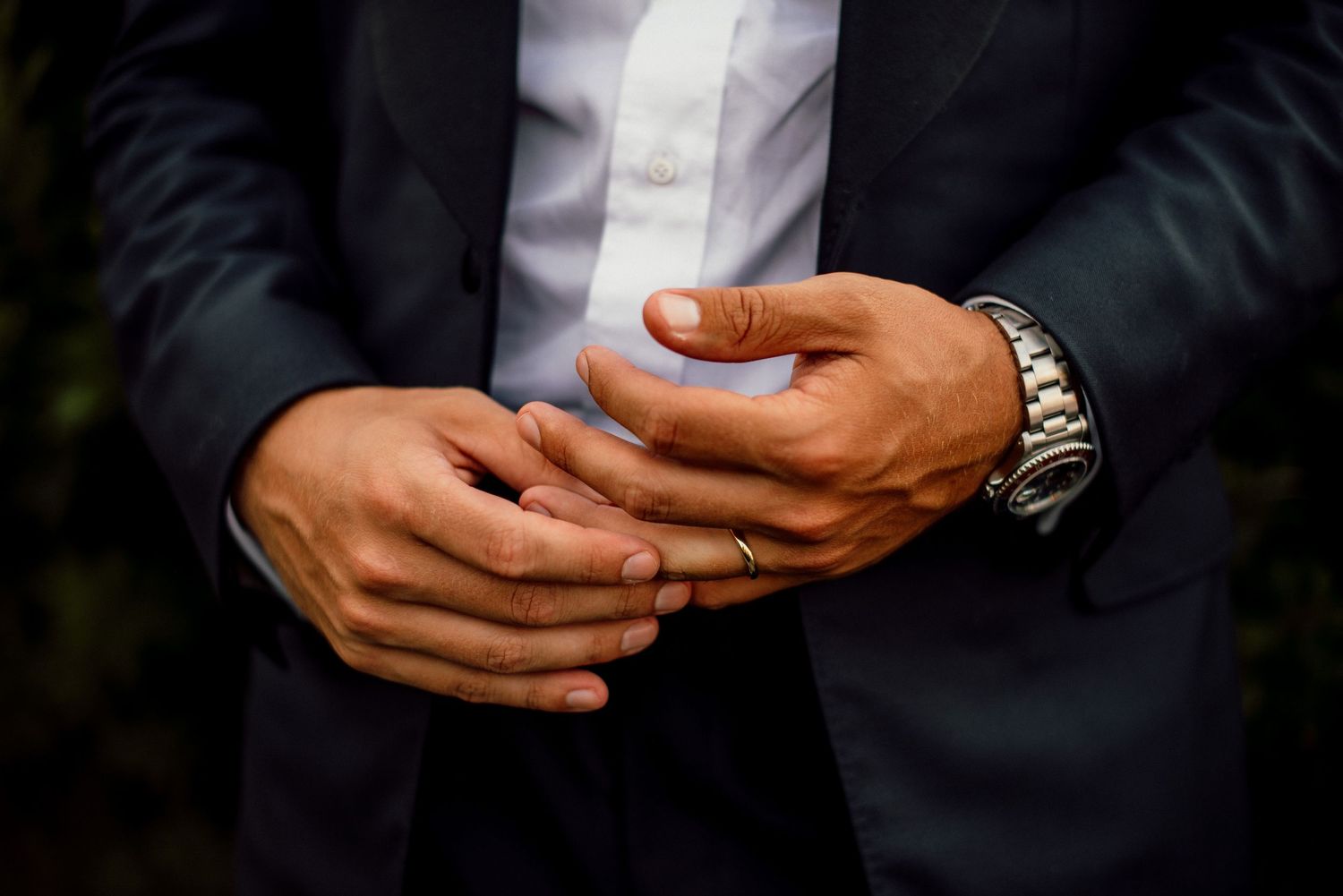 Close-up details of formal attire and hands at a wedding celebration.