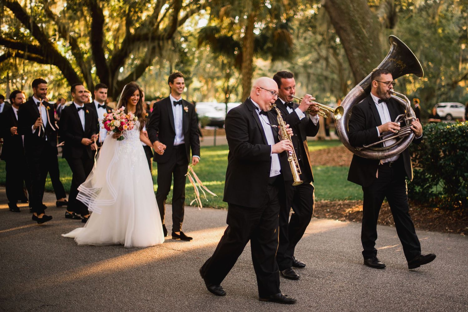 Wedding party dancing and celebrating on an outdoor dance floor during a reception at sunset.