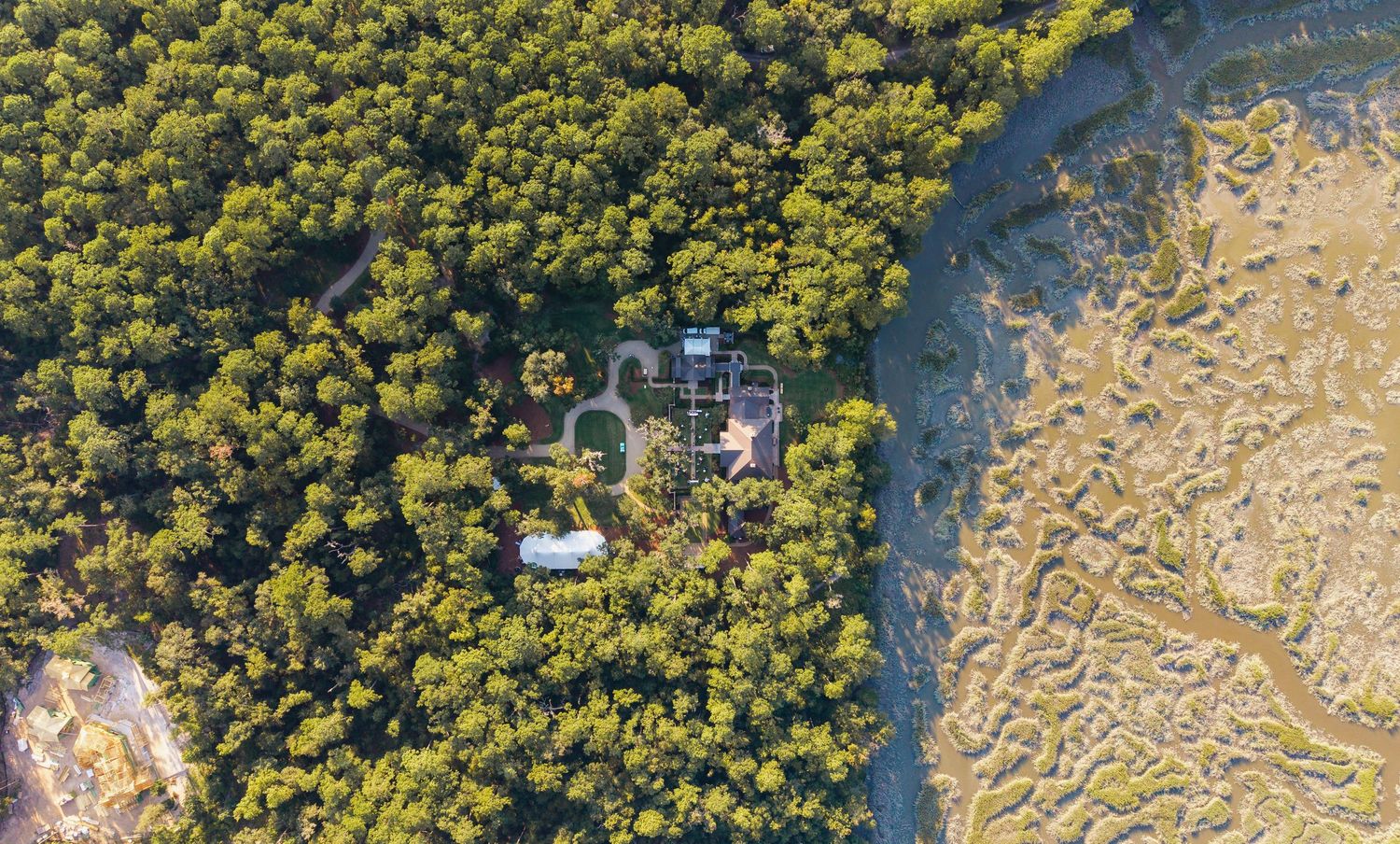 Aerial view of a winding river cutting through dense forest and sandy terrain creates natural patterns from above.