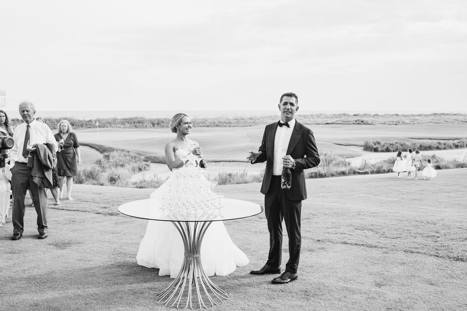 A couple shares a romantic moment on a scenic hilltop overlooking a vast landscape at sunset.