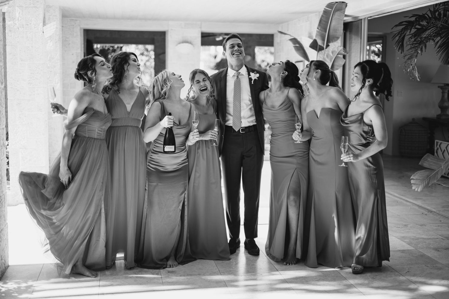 Wedding party poses together in formal attire for black and white group photo.