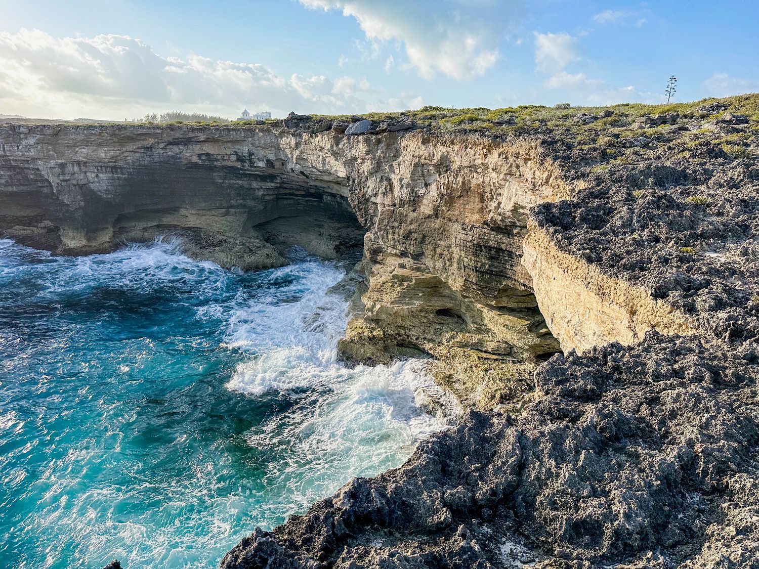 Dramatic rocky coastline of Eleuthera with waves crashing against limestone cliffs and turquoise waters below.
