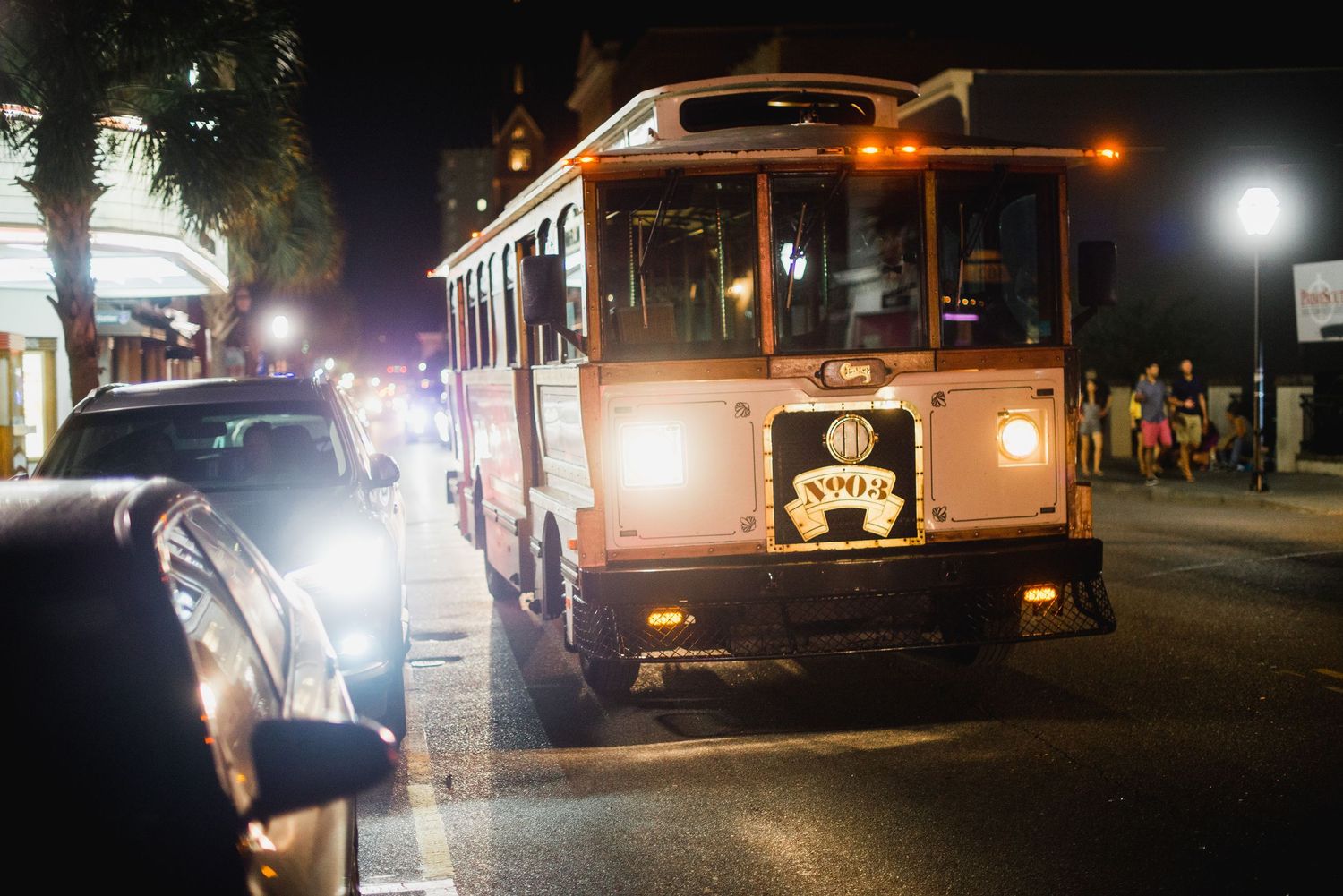 Food trucks parked at night with glowing lights and customers waiting to order in an urban setting.