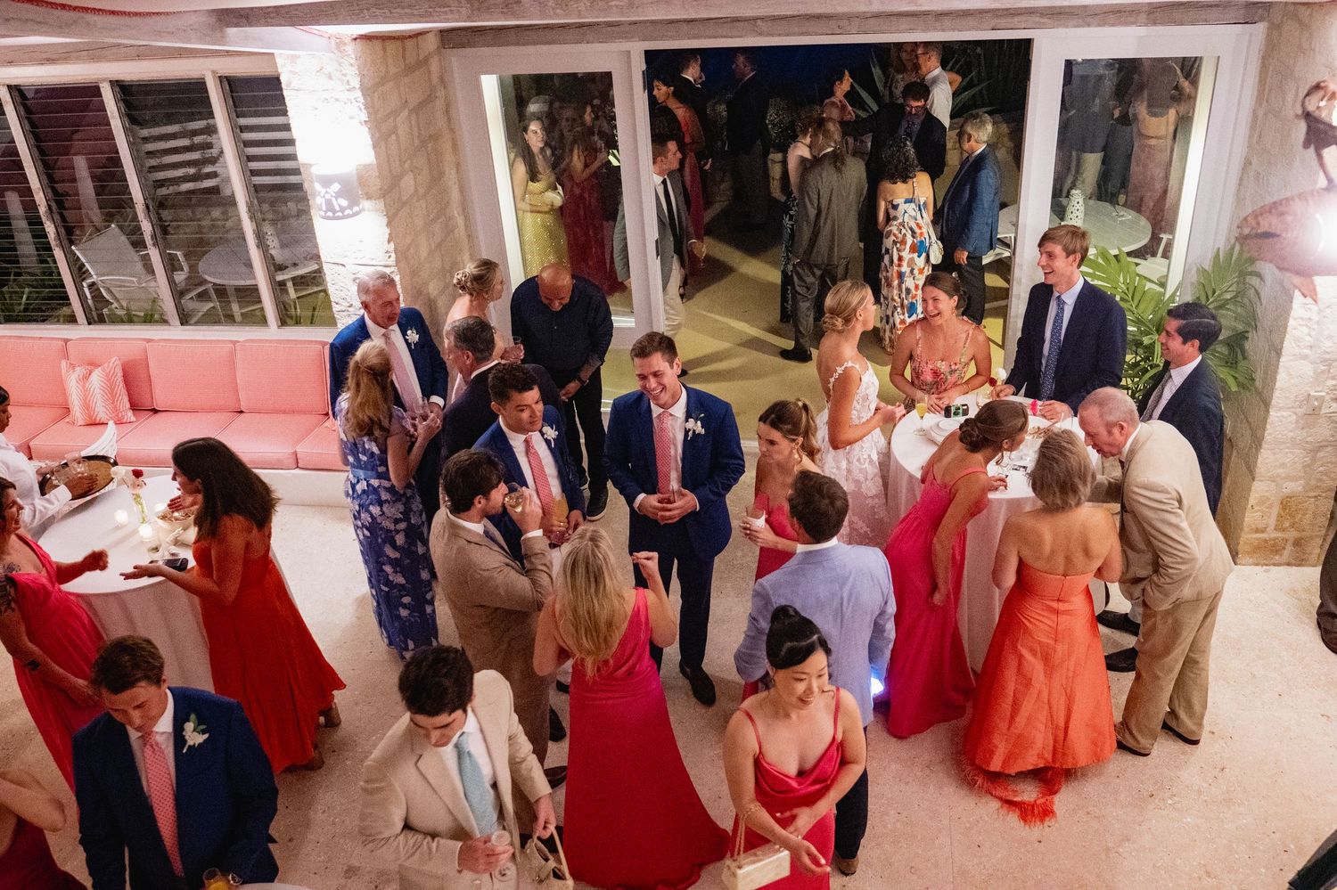 Wedding reception party with guests dancing and mingling in a pink-lit indoor venue.