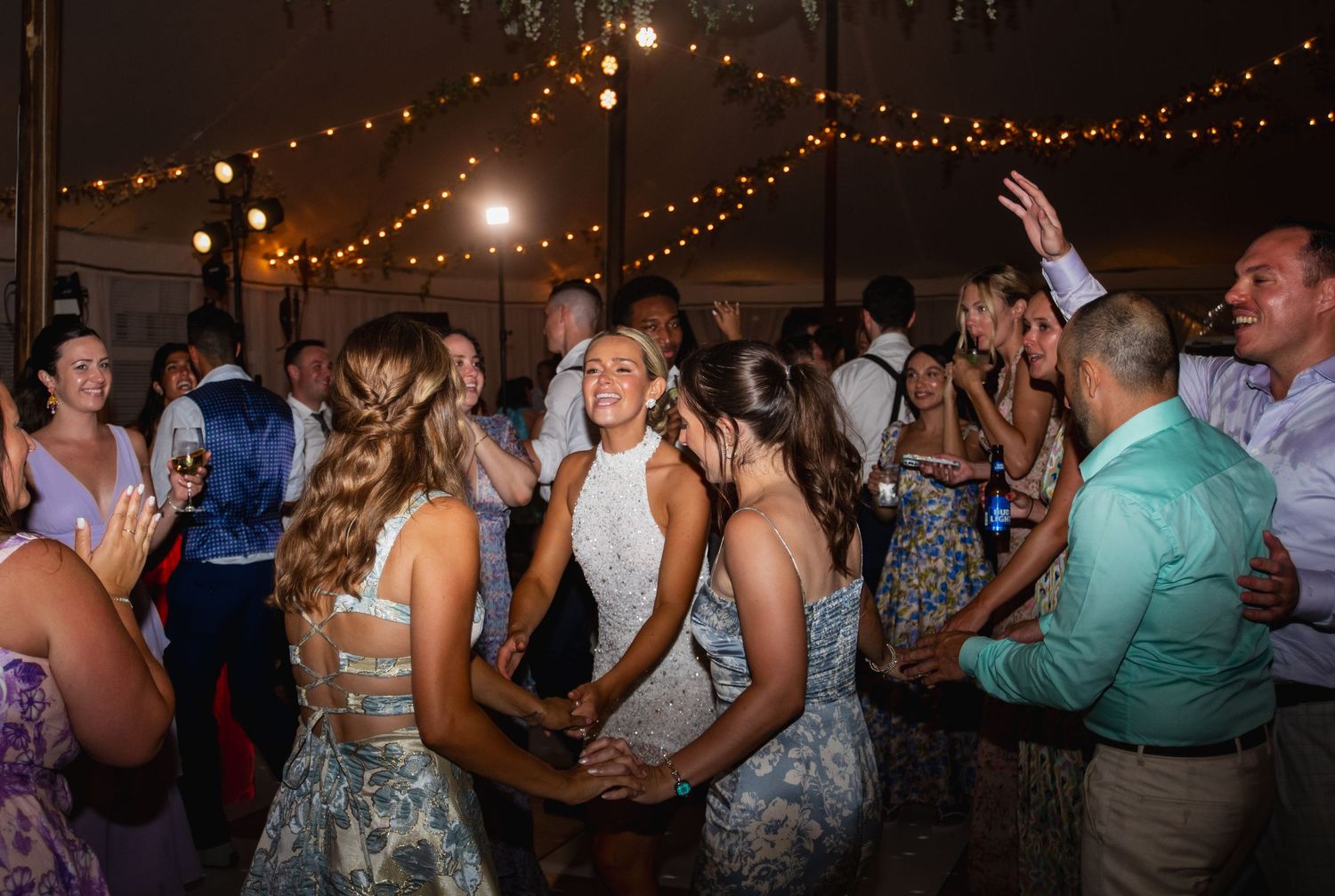 Wedding reception dance party with string lights creating a warm ambiance overhead.