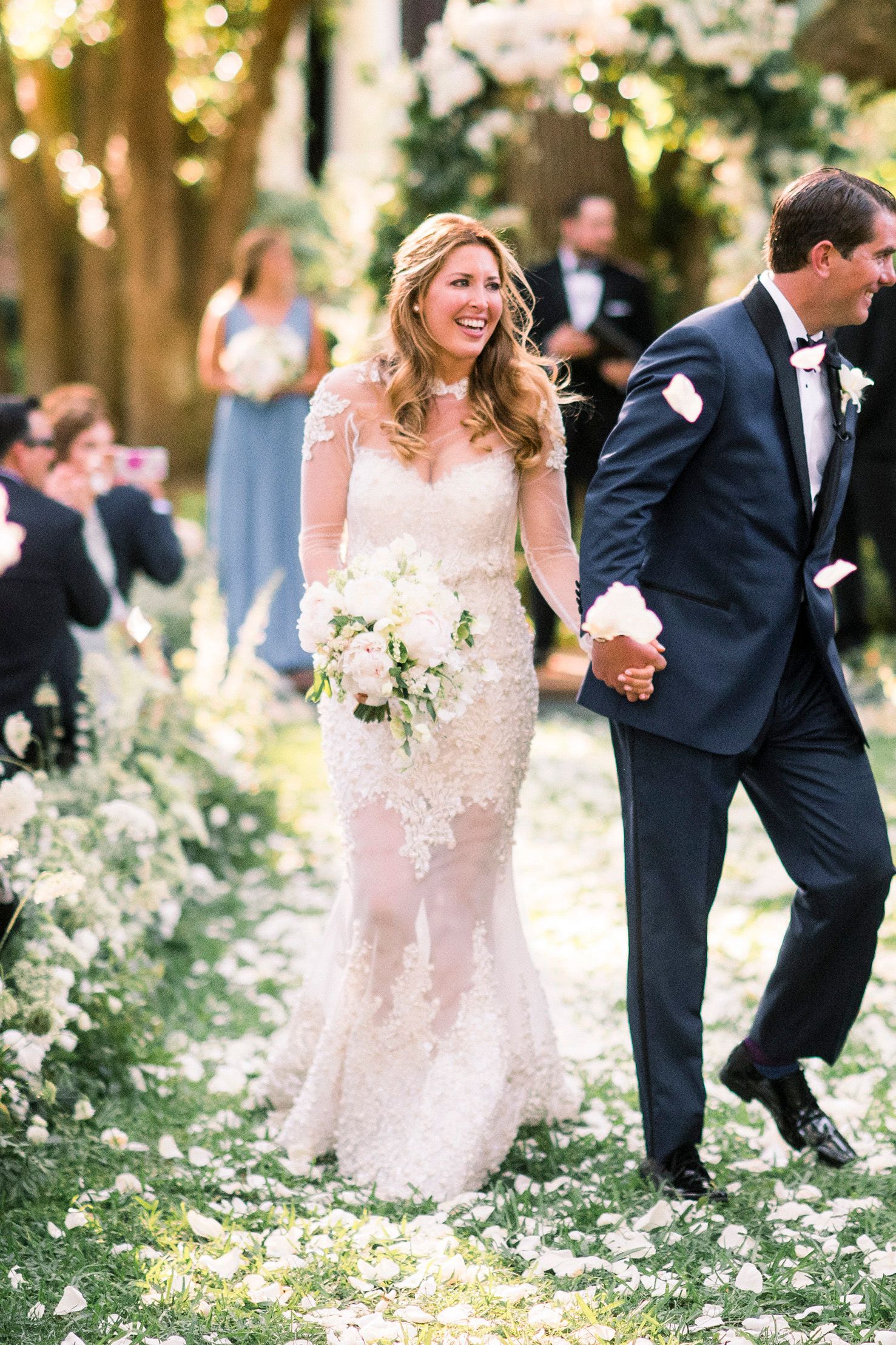 Playful wedding couple dancing among blooming flowers in garden setting.