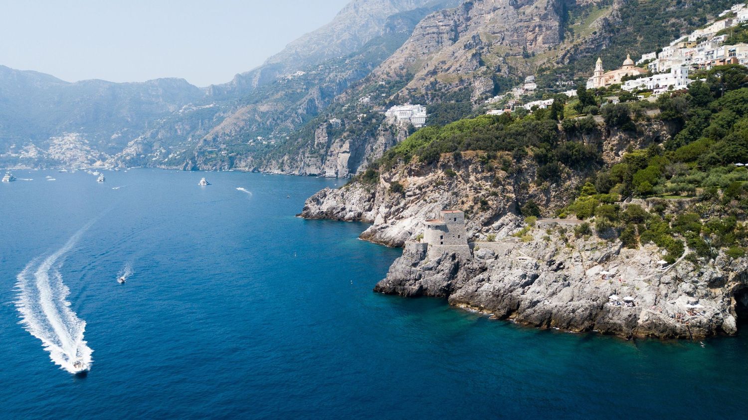 Panoramic view of the Amalfi Coast with steep cliffs, blue Mediterranean waters, and coastal villages.