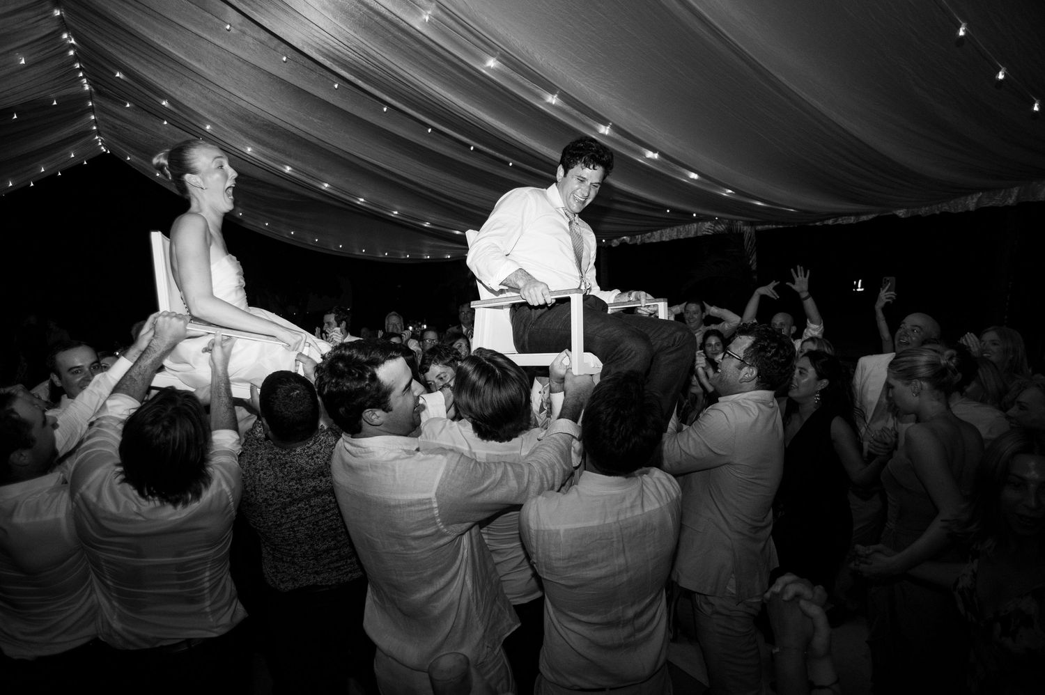 Black and white photo of wedding guests dancing and celebrating.