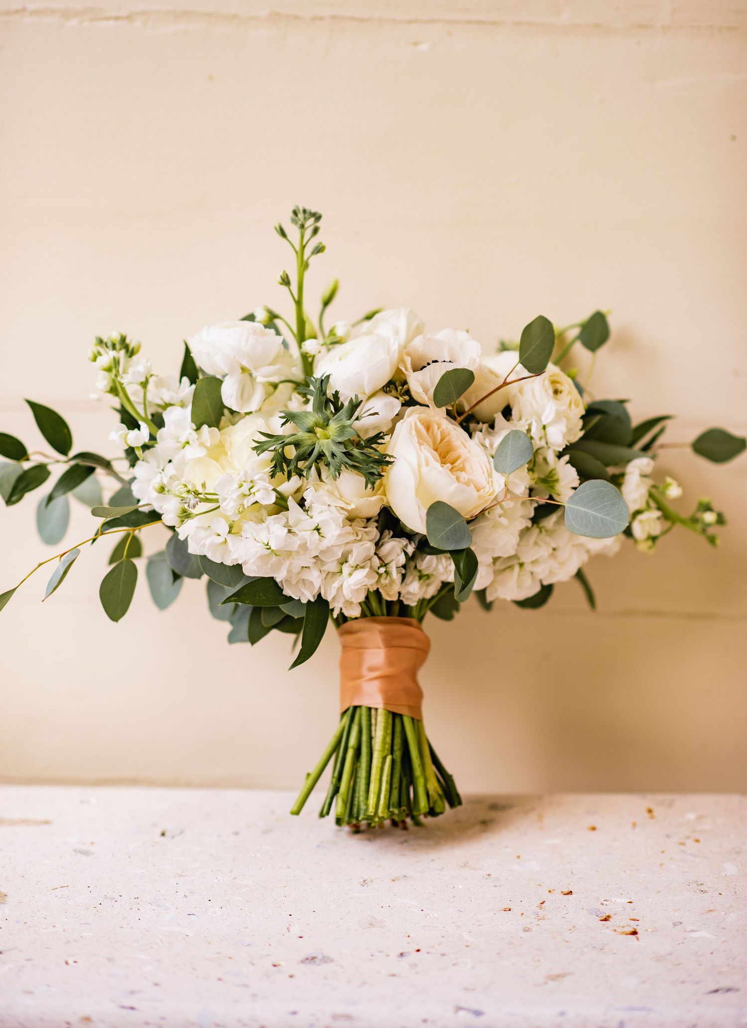 A romantic white floral bouquet with eucalyptus leaves arranged in a sequence showing different angles on a light surface.