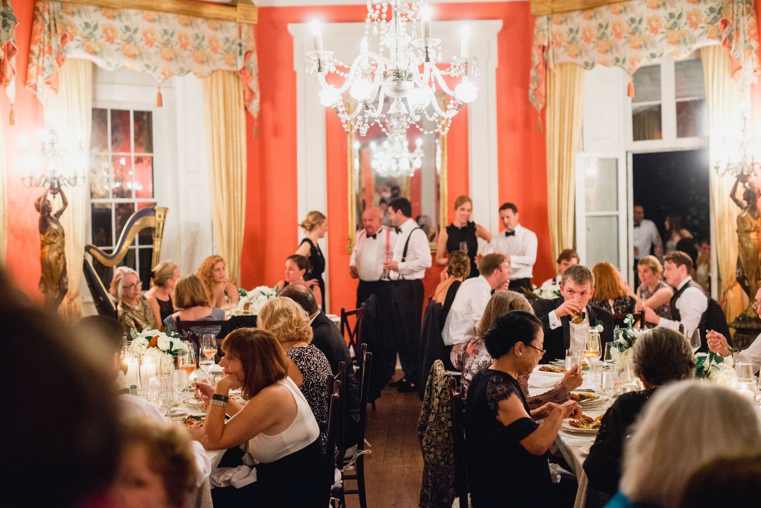 Wedding guests dance and celebrate on a dance floor in an elegant coral-colored ballroom during an evening reception.