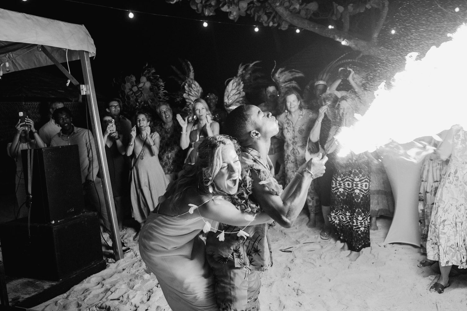 Silhouettes of people dancing at a nighttime beach party celebration.