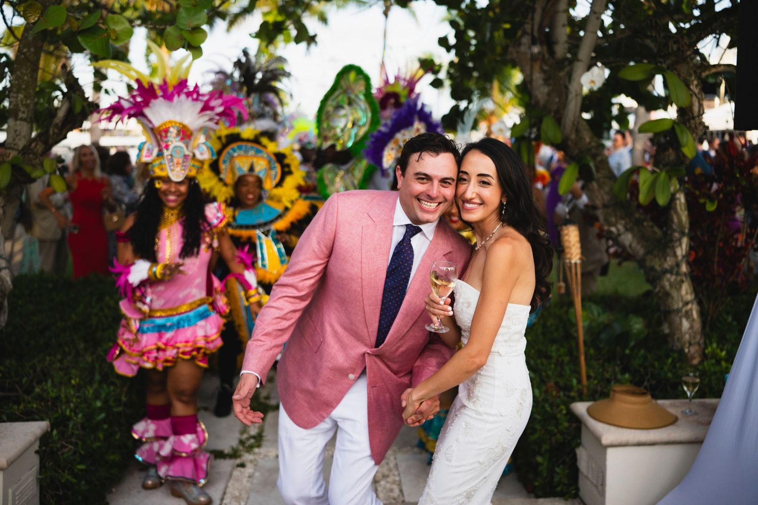 Tropical wedding celebration in a lush garden setting with vibrant pink and yellow floral decorations.