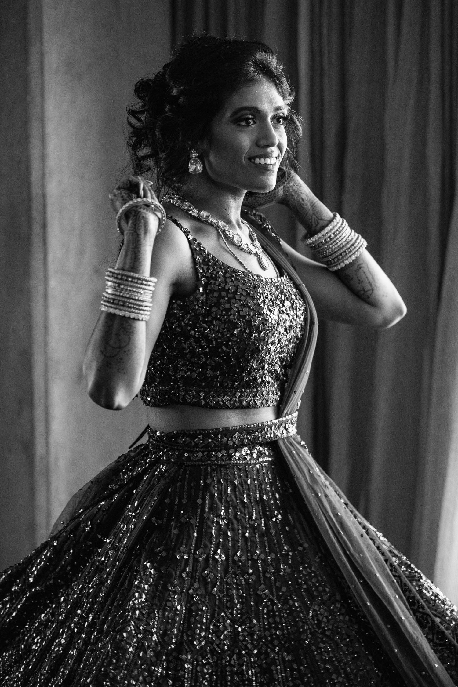 A black and white portrait of someone wearing a sparkling formal gown with traditional bangles and jewelry.