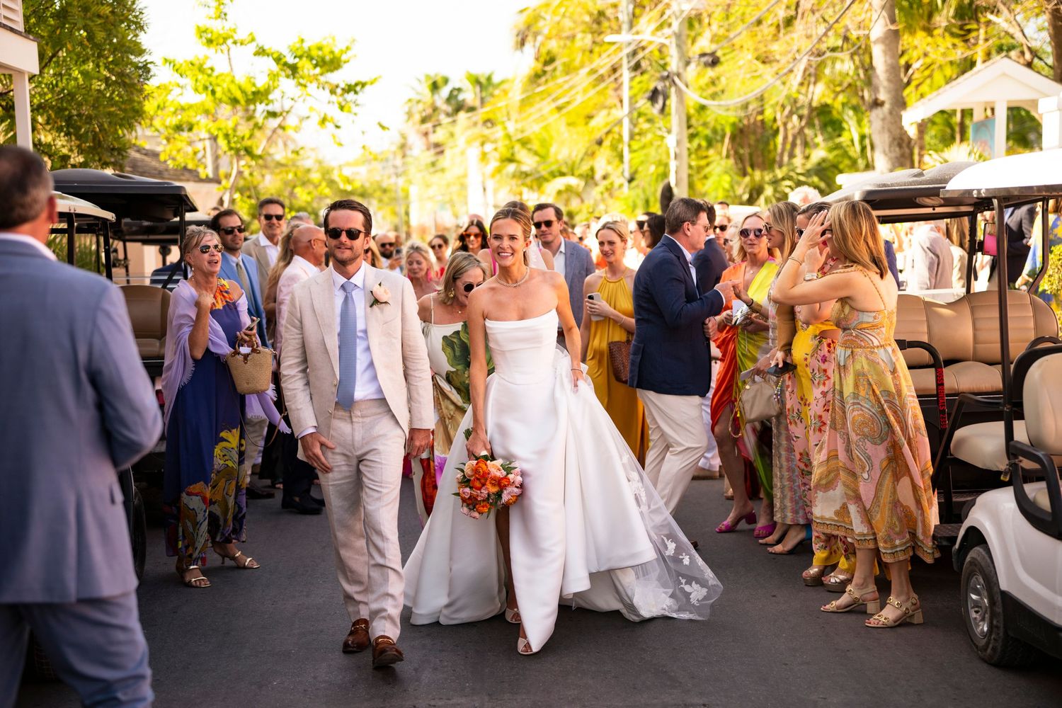 Wedding party processional through a tree-lined path in Harbour Island with guests watching from both sides.