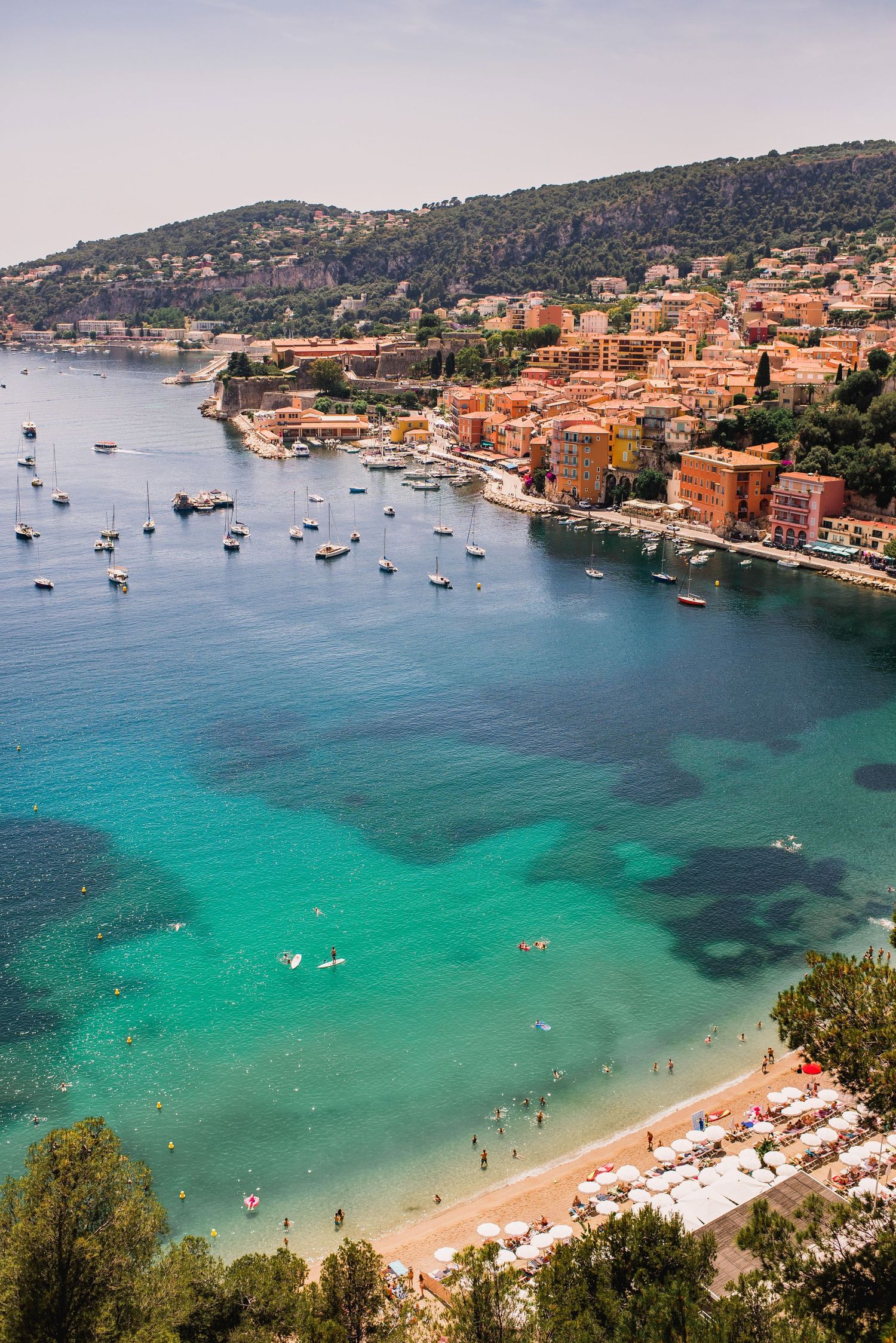 Aerial view of Mediterranean beach cove in beaulieu sur mer with turquoise waters and moored boats.
