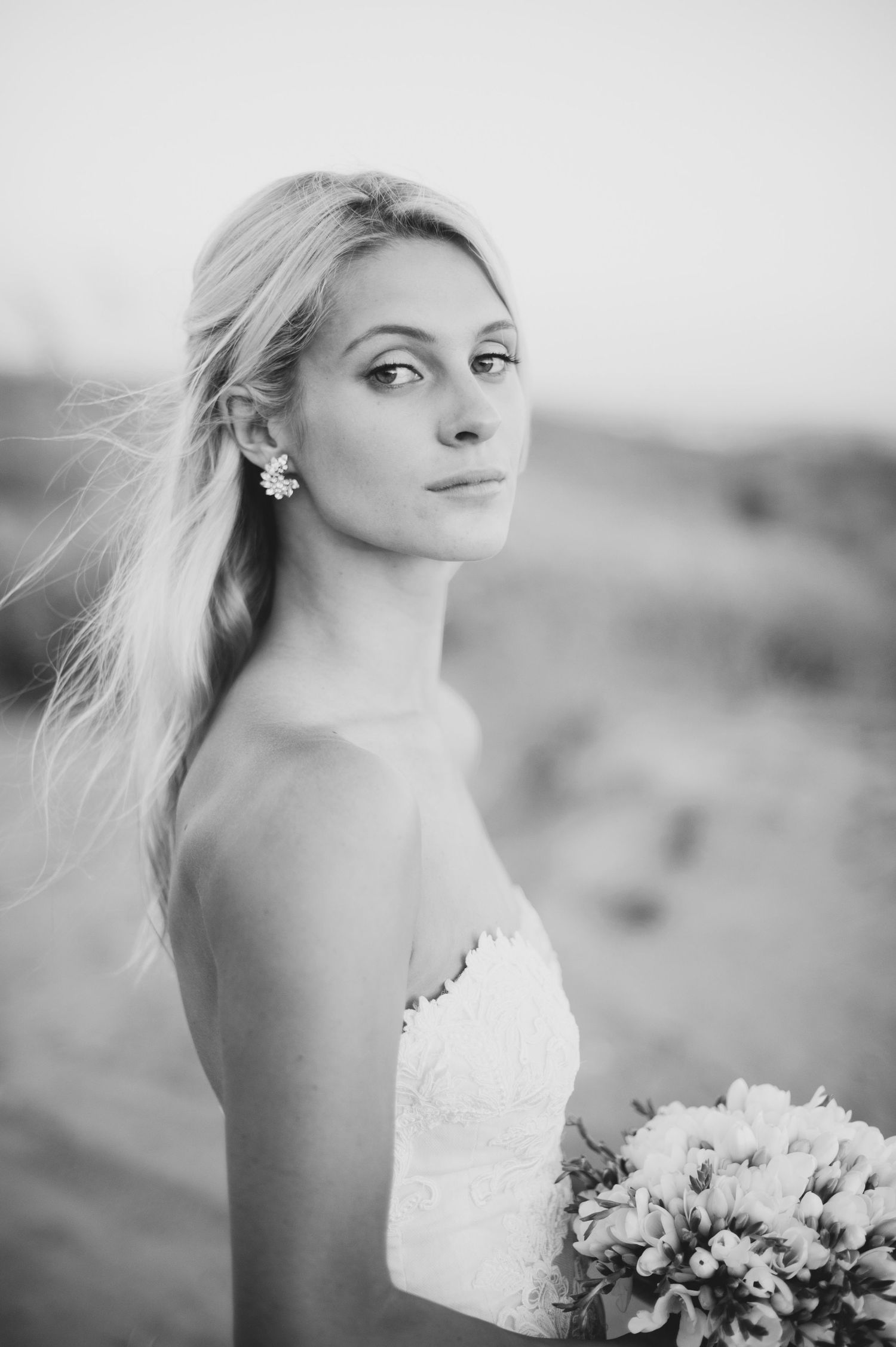 A series of black and white bridal portraits showing a strapless wedding dress and floral bouquet in an outdoor setting.