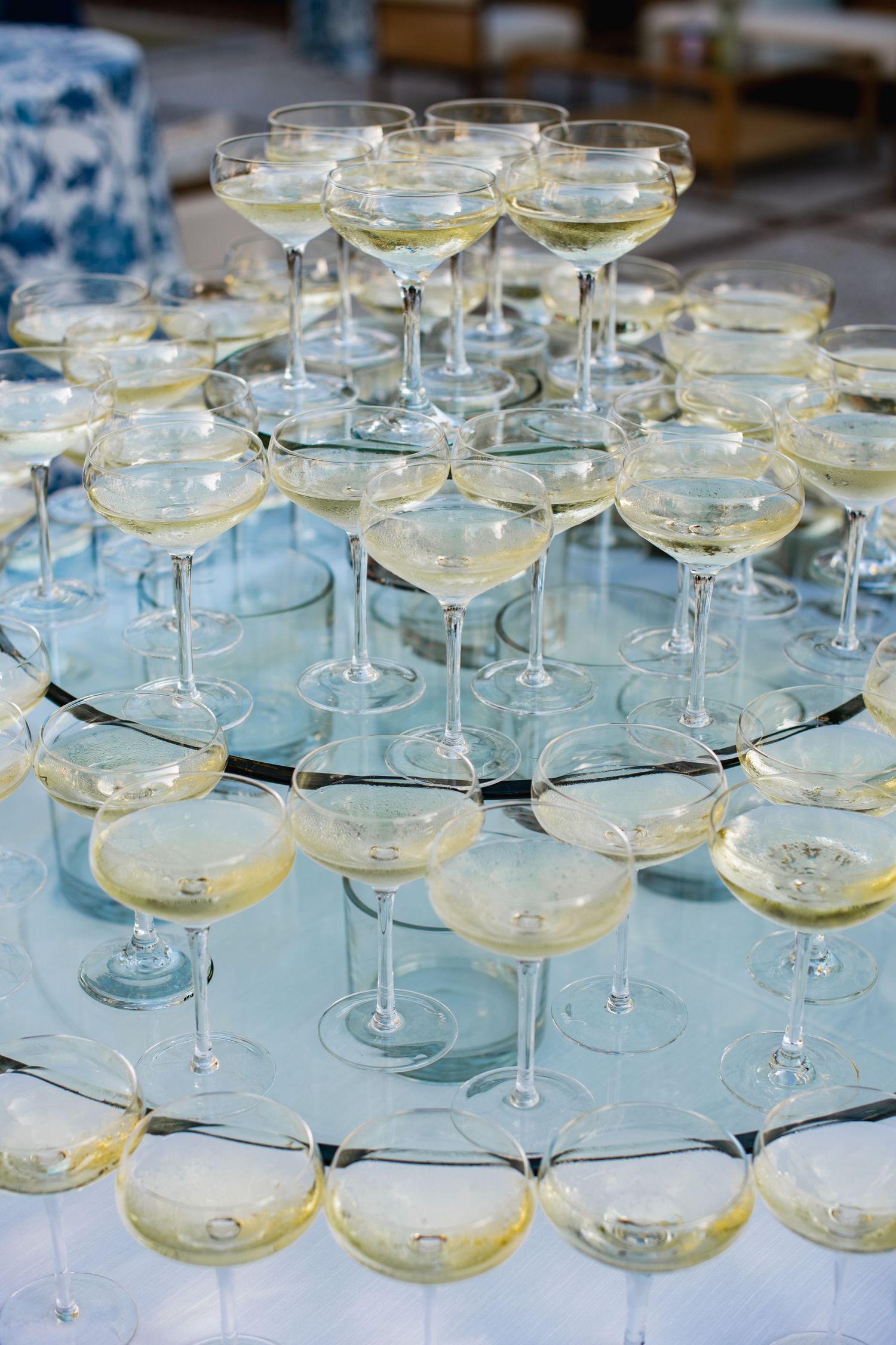 Elegant champagne tower with coupe glasses arranged in tiers on mirrored platforms filled with sparkling wine.