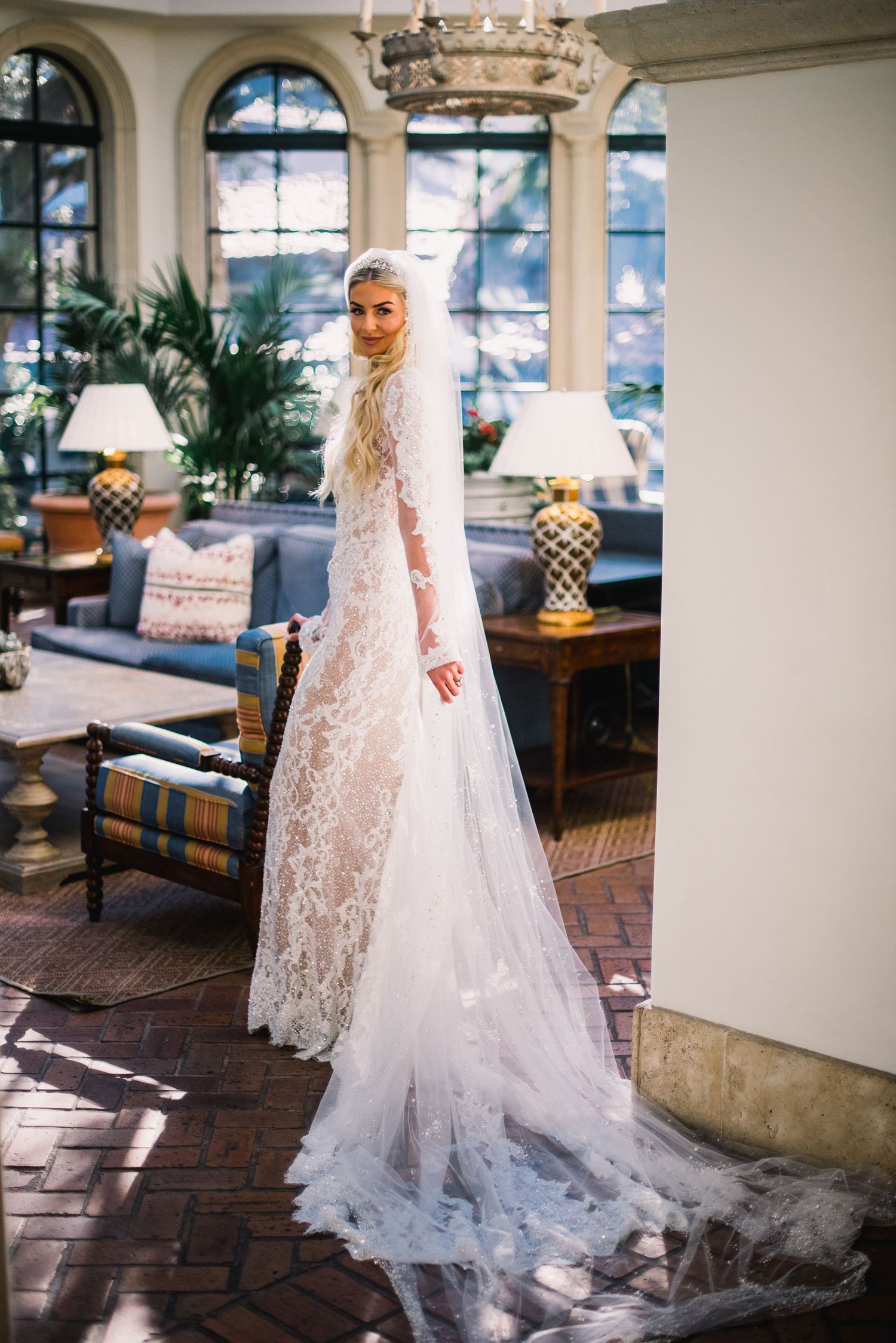 A stunning bridal gown with delicate lace details and flowing train captured in an elegant indoor setting with natural light.