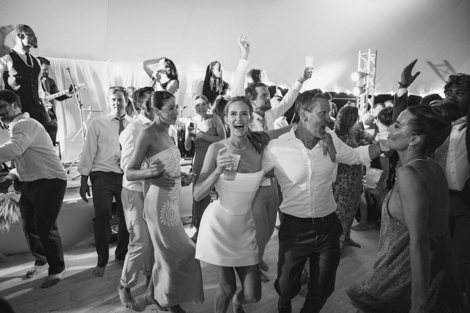 Black and white photo of wedding reception dancing with guests celebrating on the dance floor.