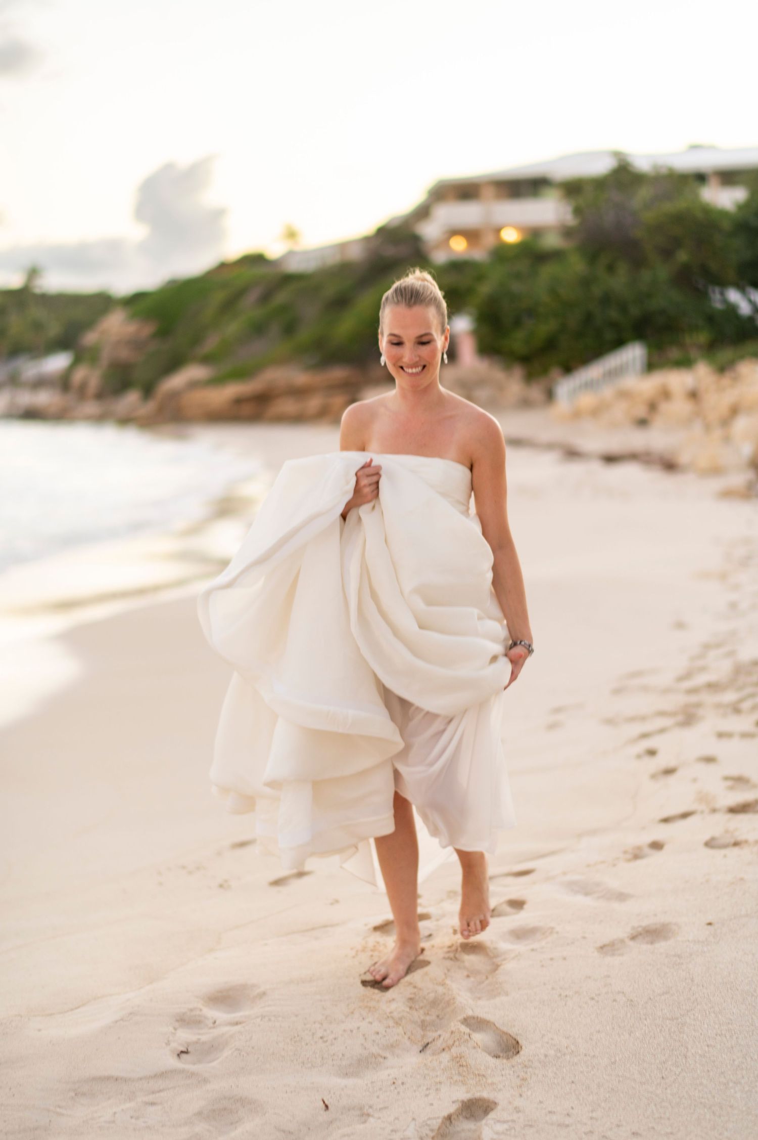 White dress flowing in the breeze on a sandy beach at sunset.