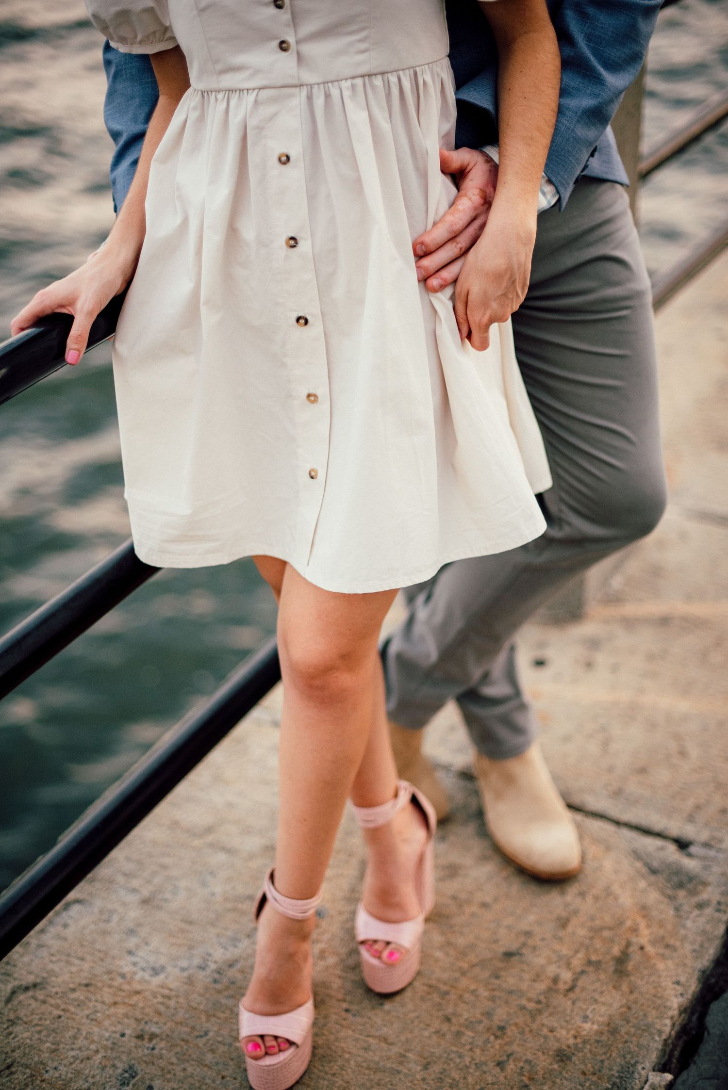 White summer dress and pink sandals detail shot against concrete background.