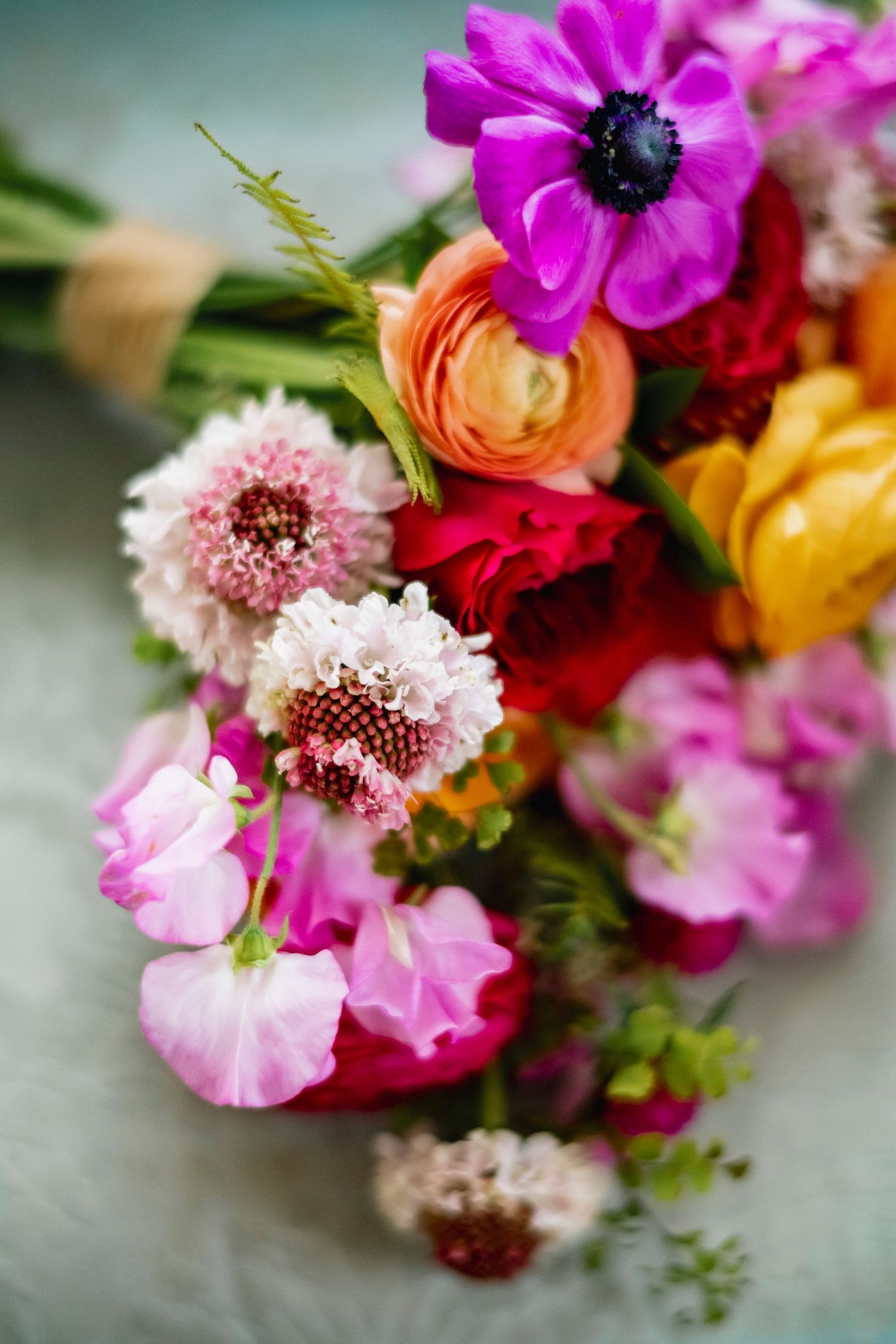 Vibrant wedding bouquet with pink anemones, ranunculus, and mixed colorful blooms.