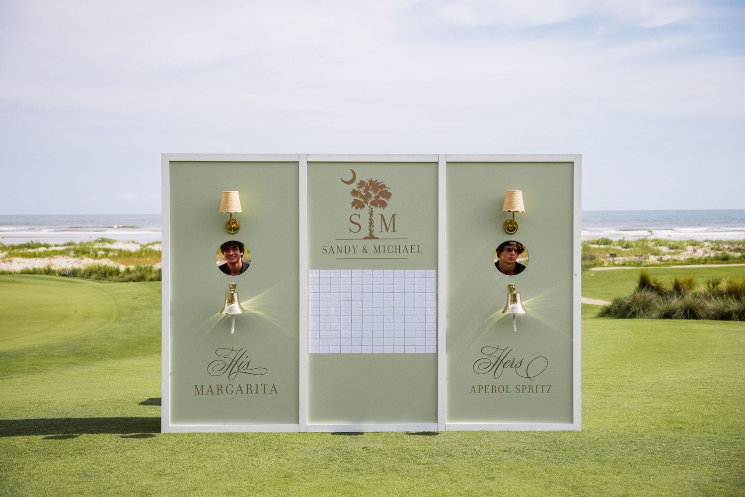 Elegant wedding venue signage and decorations displayed on a green lawn against a white tent backdrop.