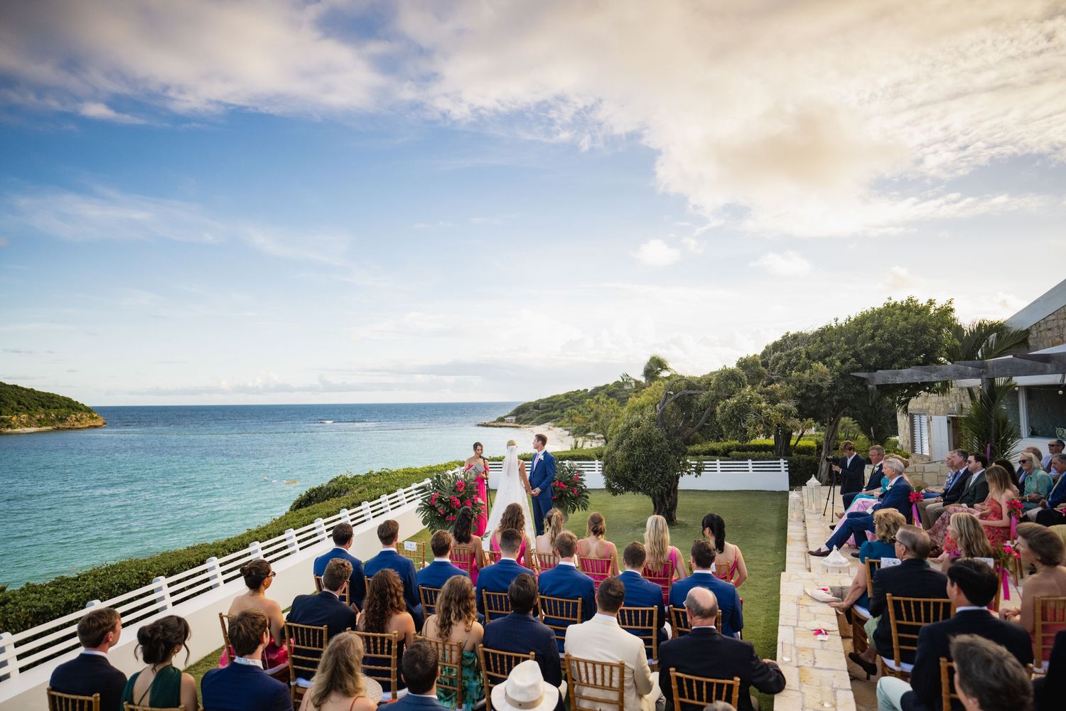 Outdoor wedding ceremony setup with guests seated overlooking ocean views.