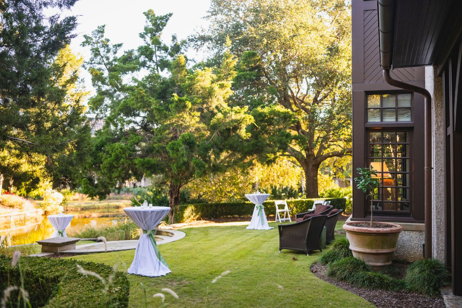 A serene garden patio setting with outdoor furniture and lush greenery illuminated by warm evening sunlight.