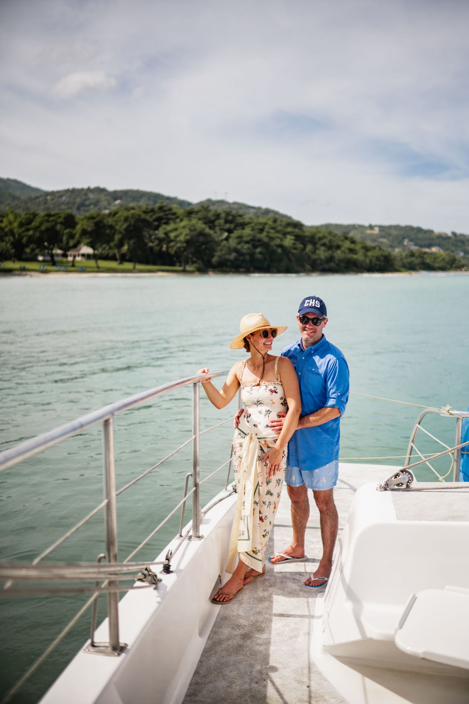 Couple enjoying a sunny day together on the deck of a boat in tropical waters with lush green islands in background.