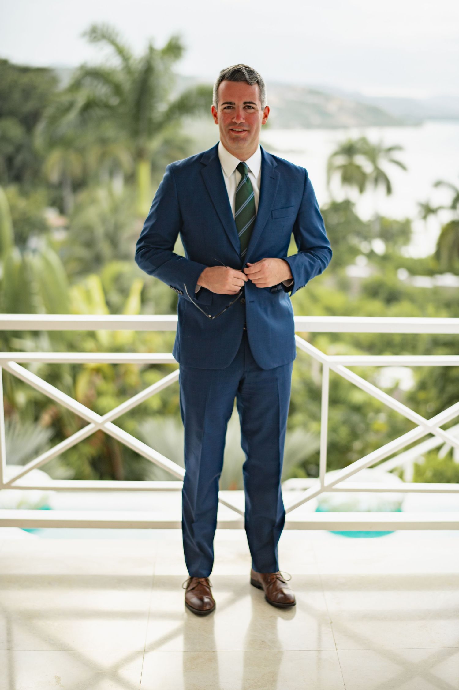A series of detail shots showing a navy blue suit with brown shoes on a white balcony with tropical palm trees in background.