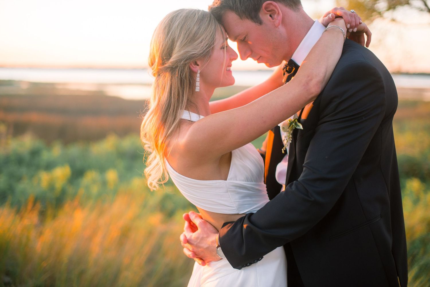 Couple shares romantic kisses at sunset in a golden field during their wedding photo session.