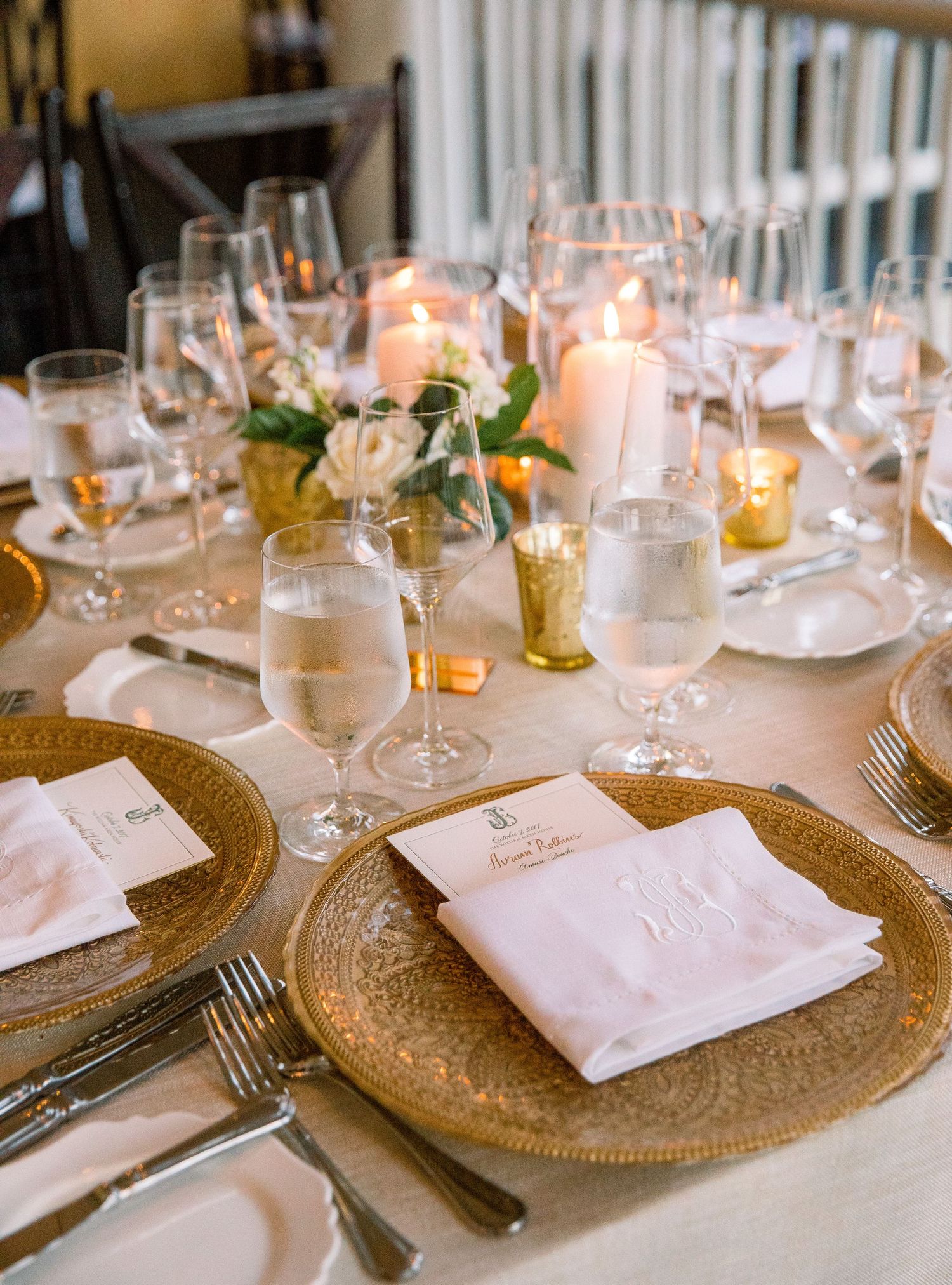Elegant wedding table settings with gold charger plates, white napkins, and glowing candles create a romantic atmosphere.